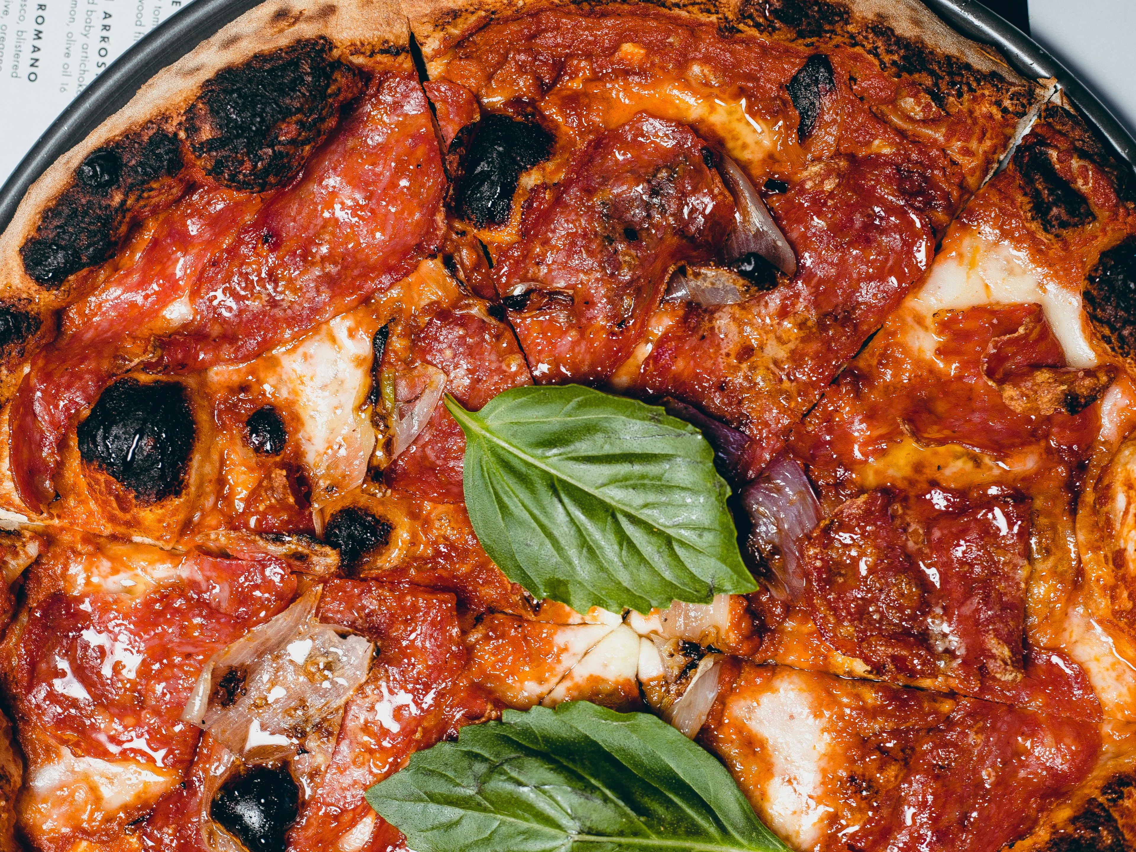 close of a Neapolitan margherita pizza with fresh basil leaves on top