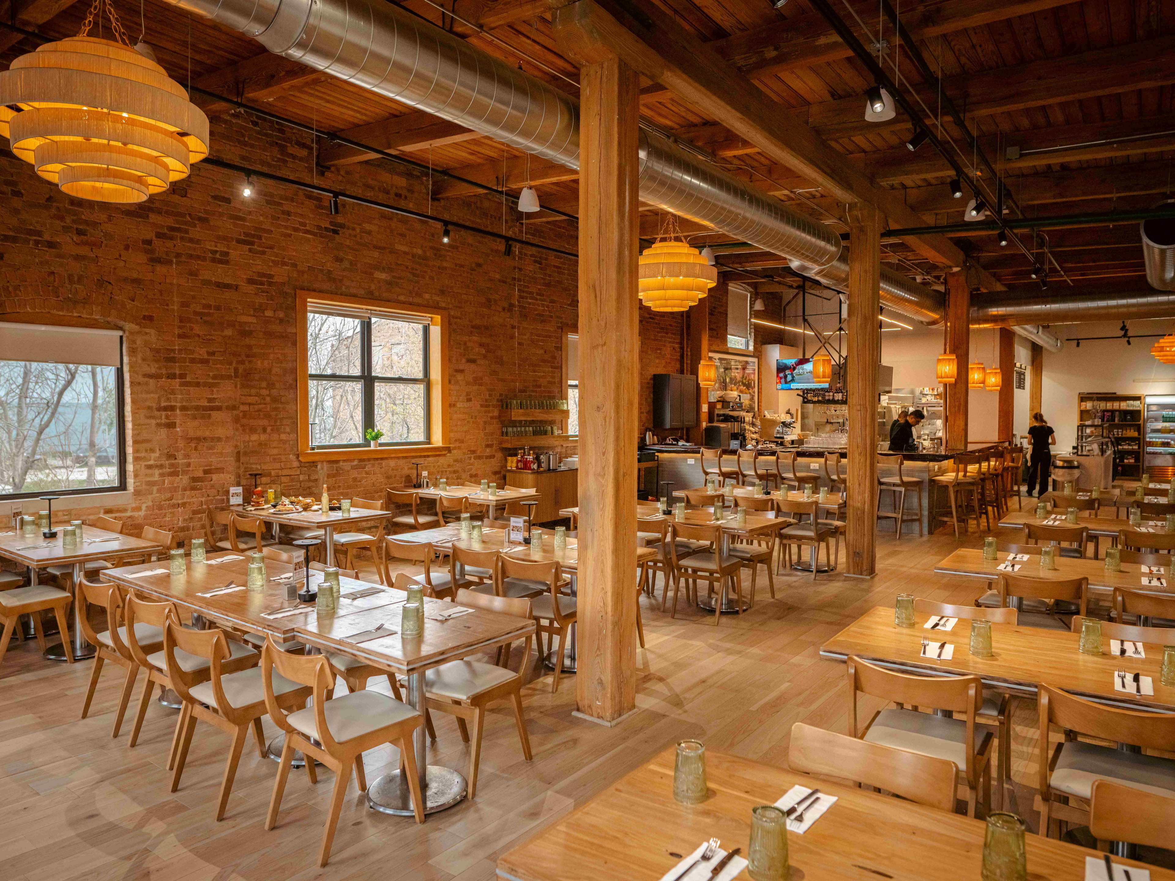 Large high ceilinged brick dining room with wooden tables and exposed beams