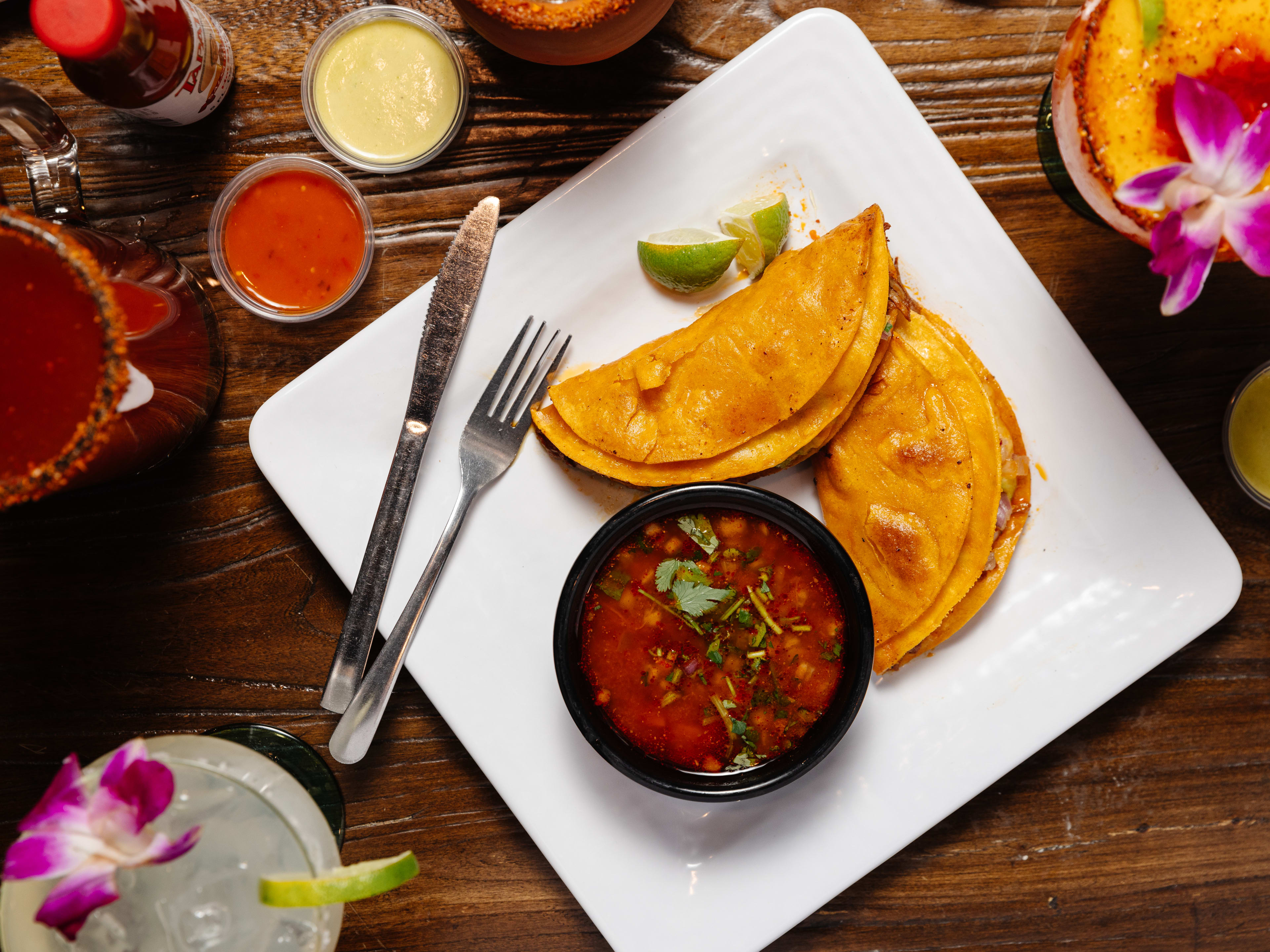 Quesabirria tacos with various salsas at El Burrito Mercado