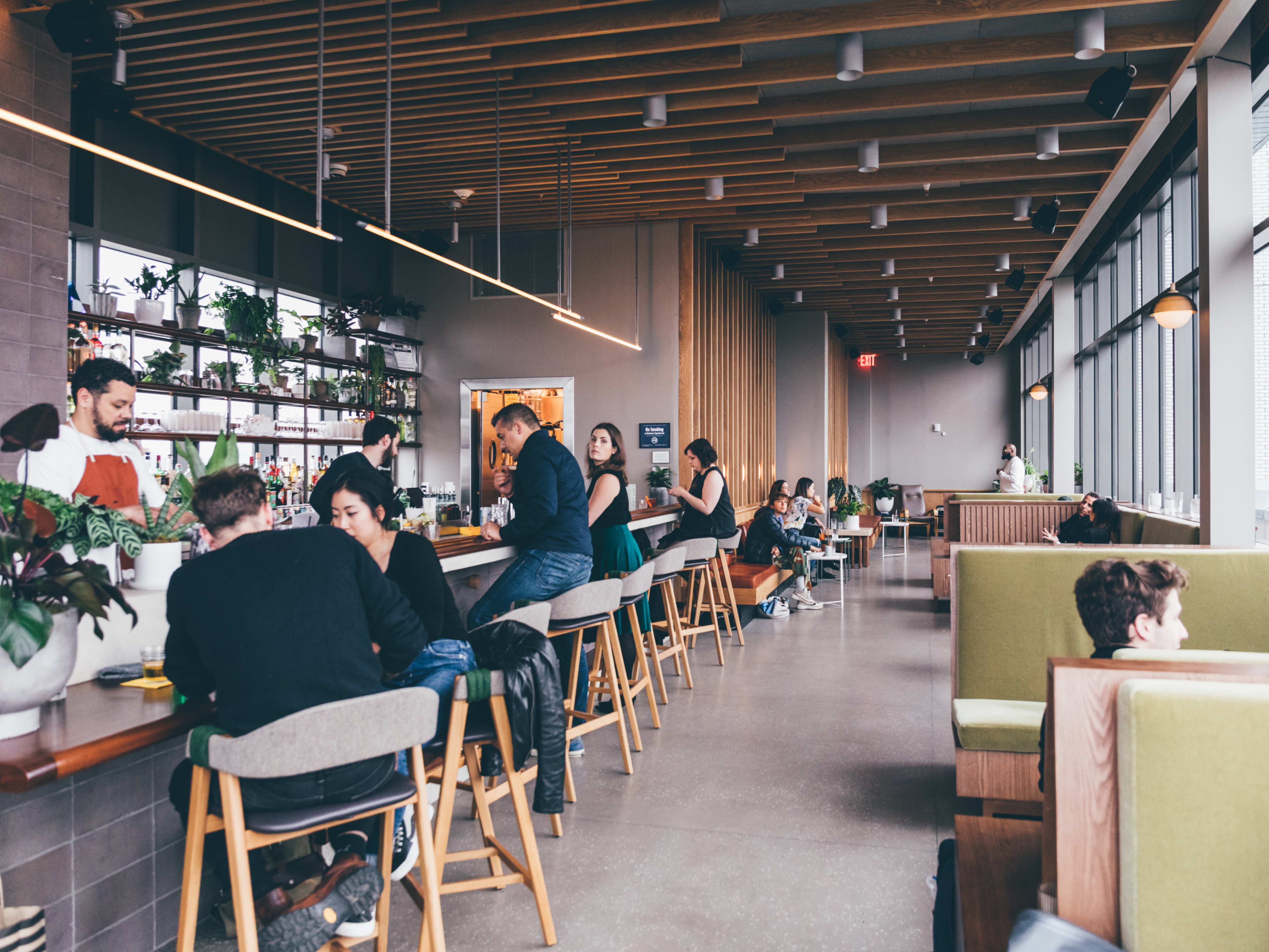 Last Light rooftop interiors with people seated at the bar on the left and green booth seating on the right