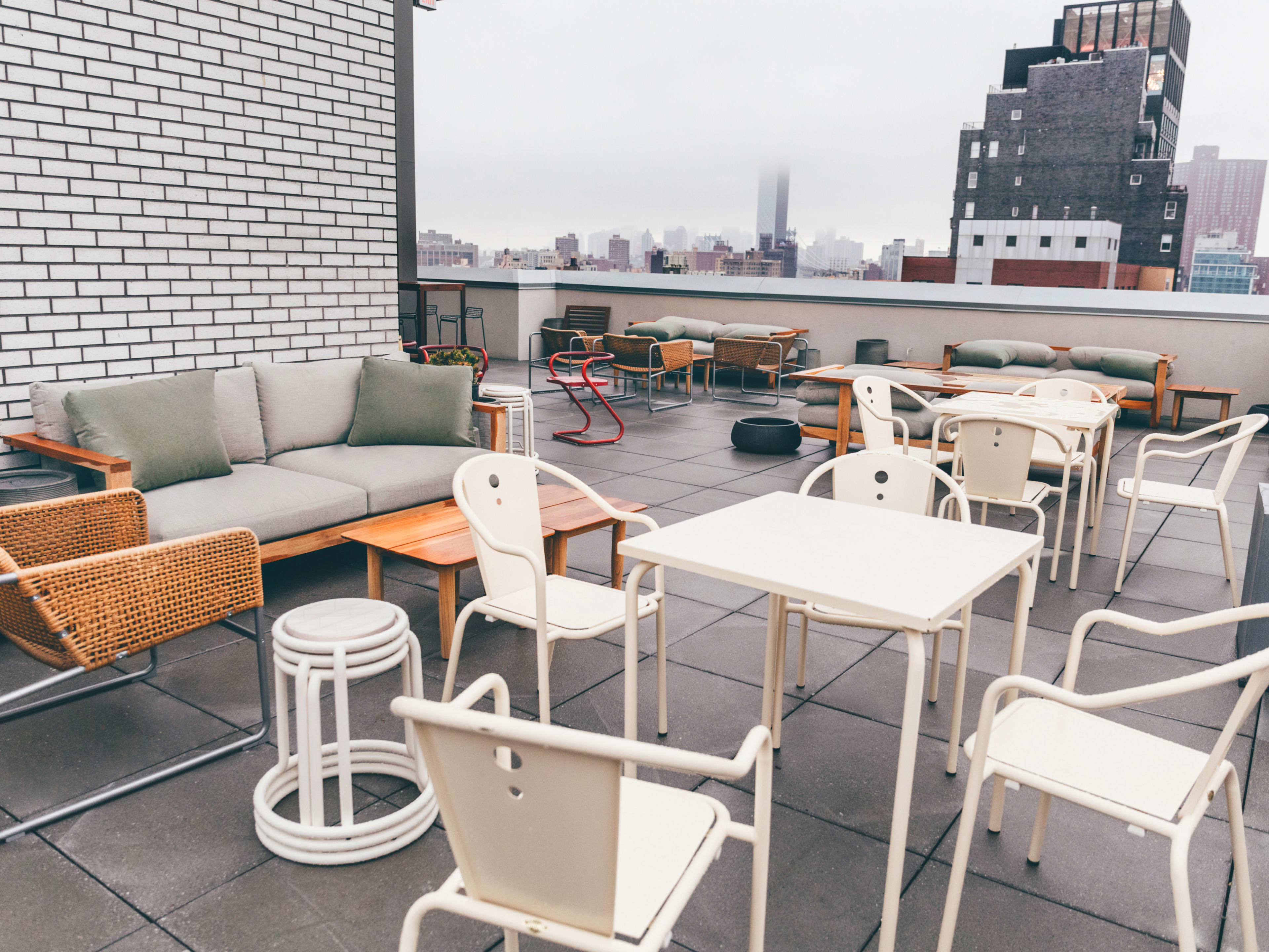 Last Light rooftop with white metal tables and chairs as well as couches and other outdoor patio furniture