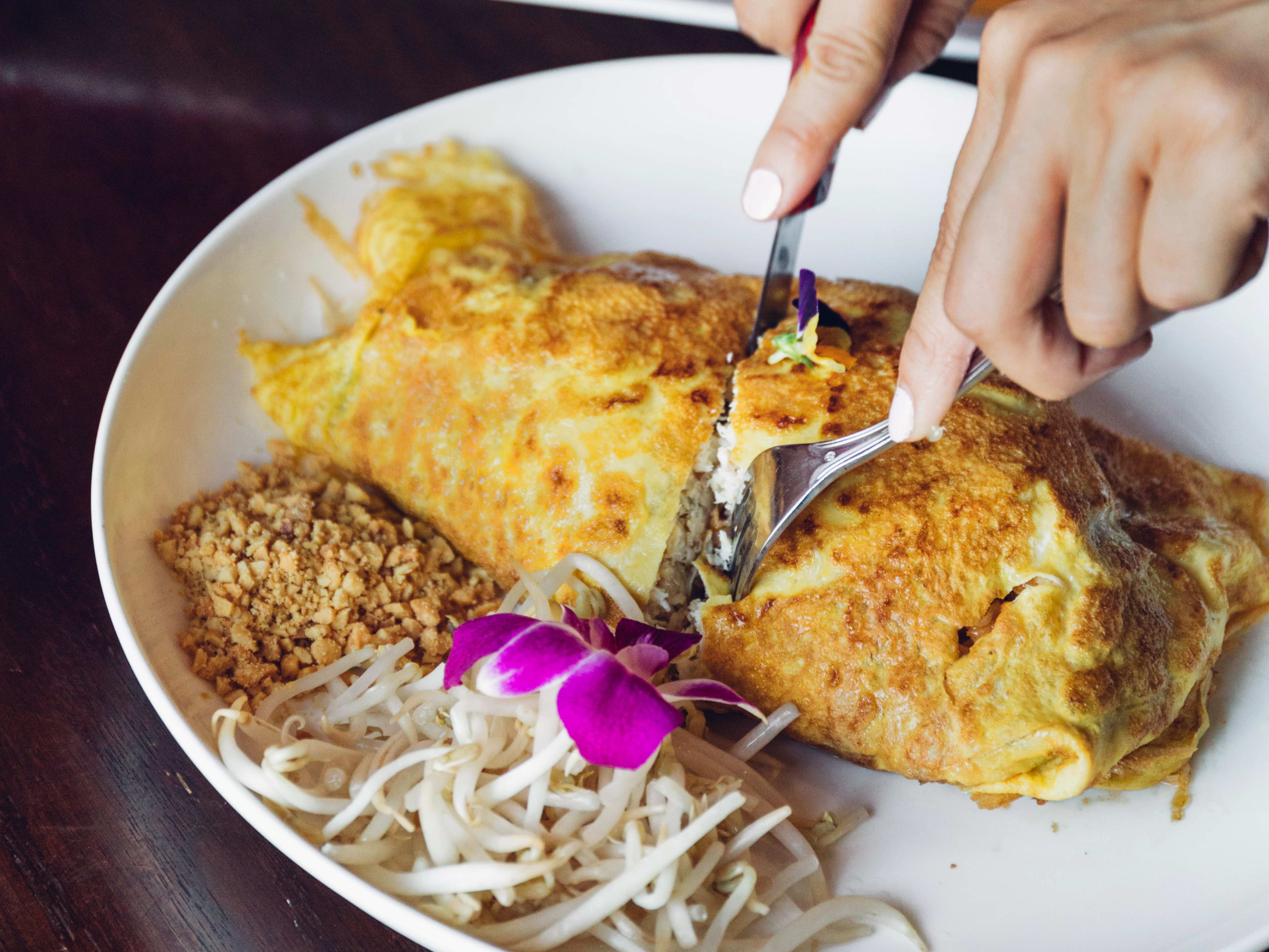 Fork and knife cutting into omurice at Nur Thai