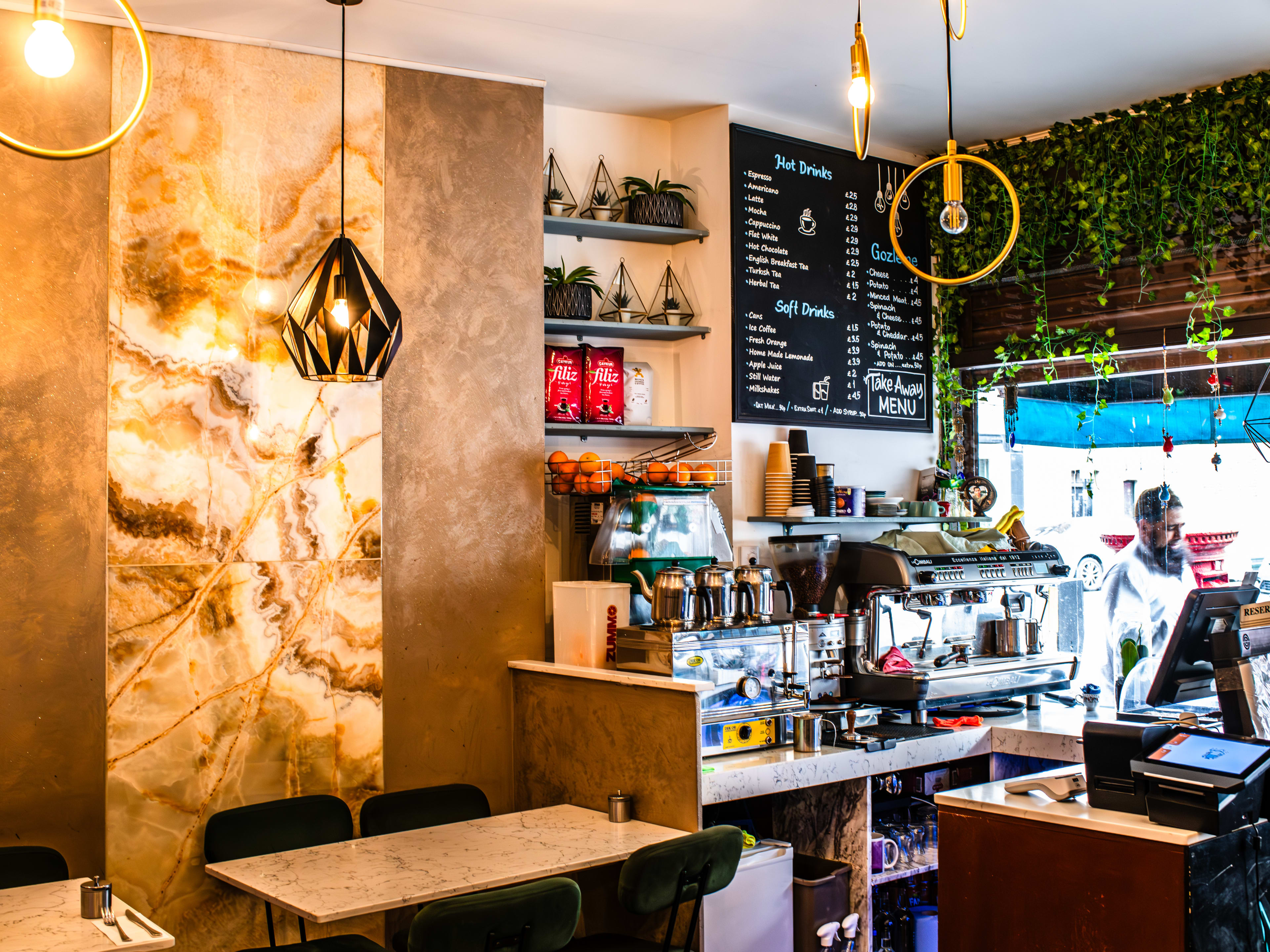 The till and coffee maker station in a bright dining room.