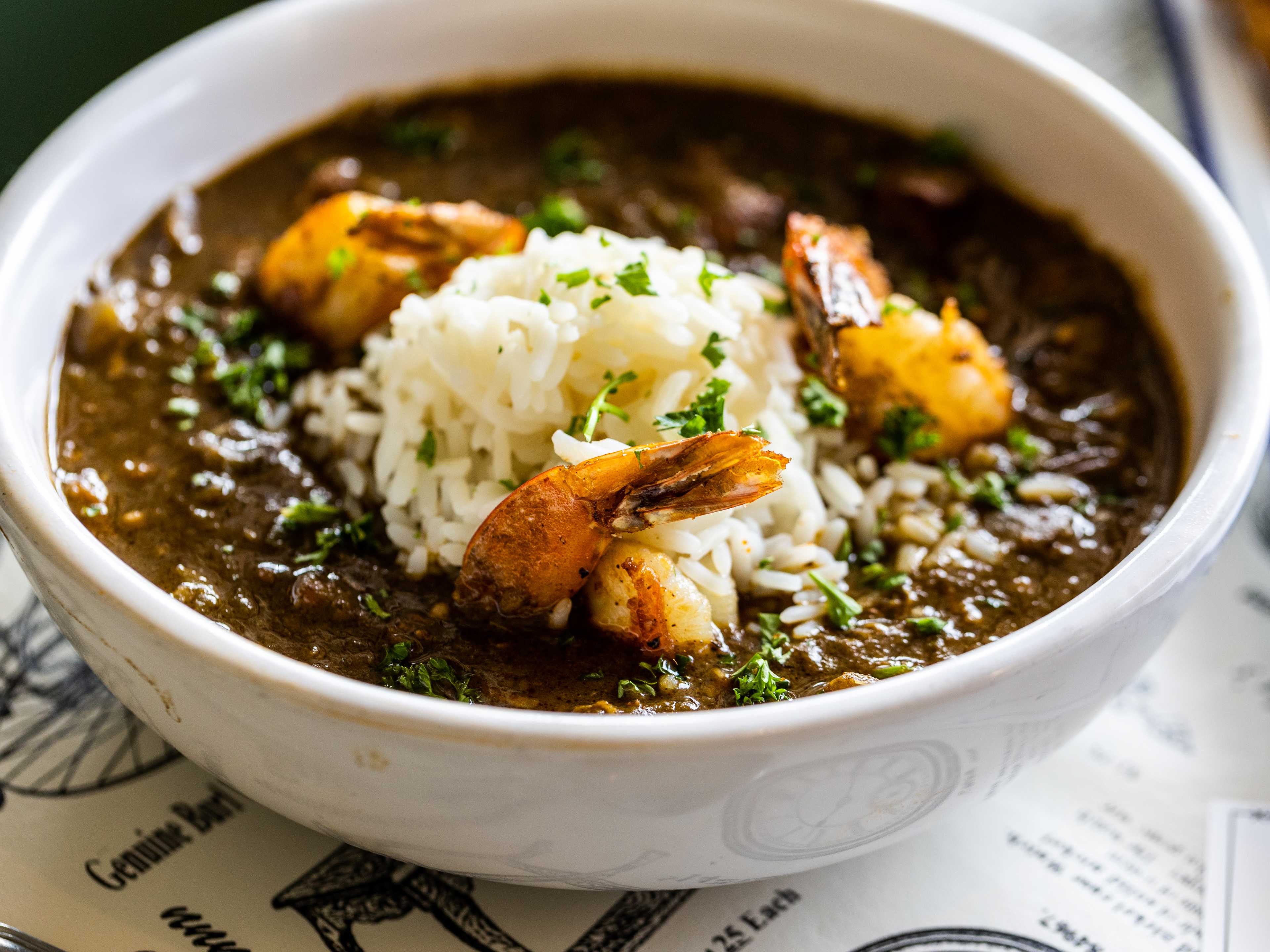 bowl of gumbo with shrimp topping the bowl and white rice in the center