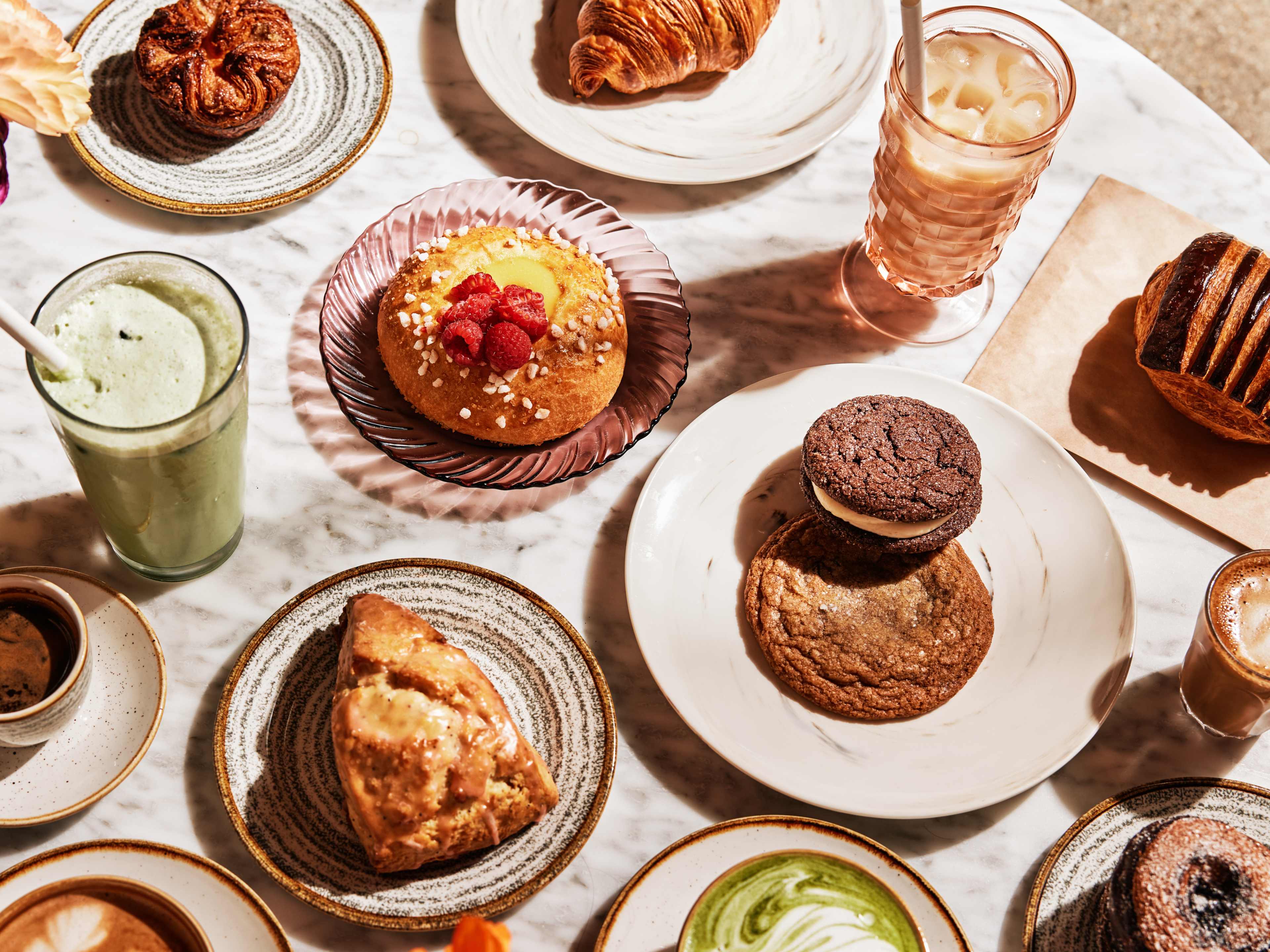 Tabletop covered with coffees, cookies, scones, croissants, and other pastries