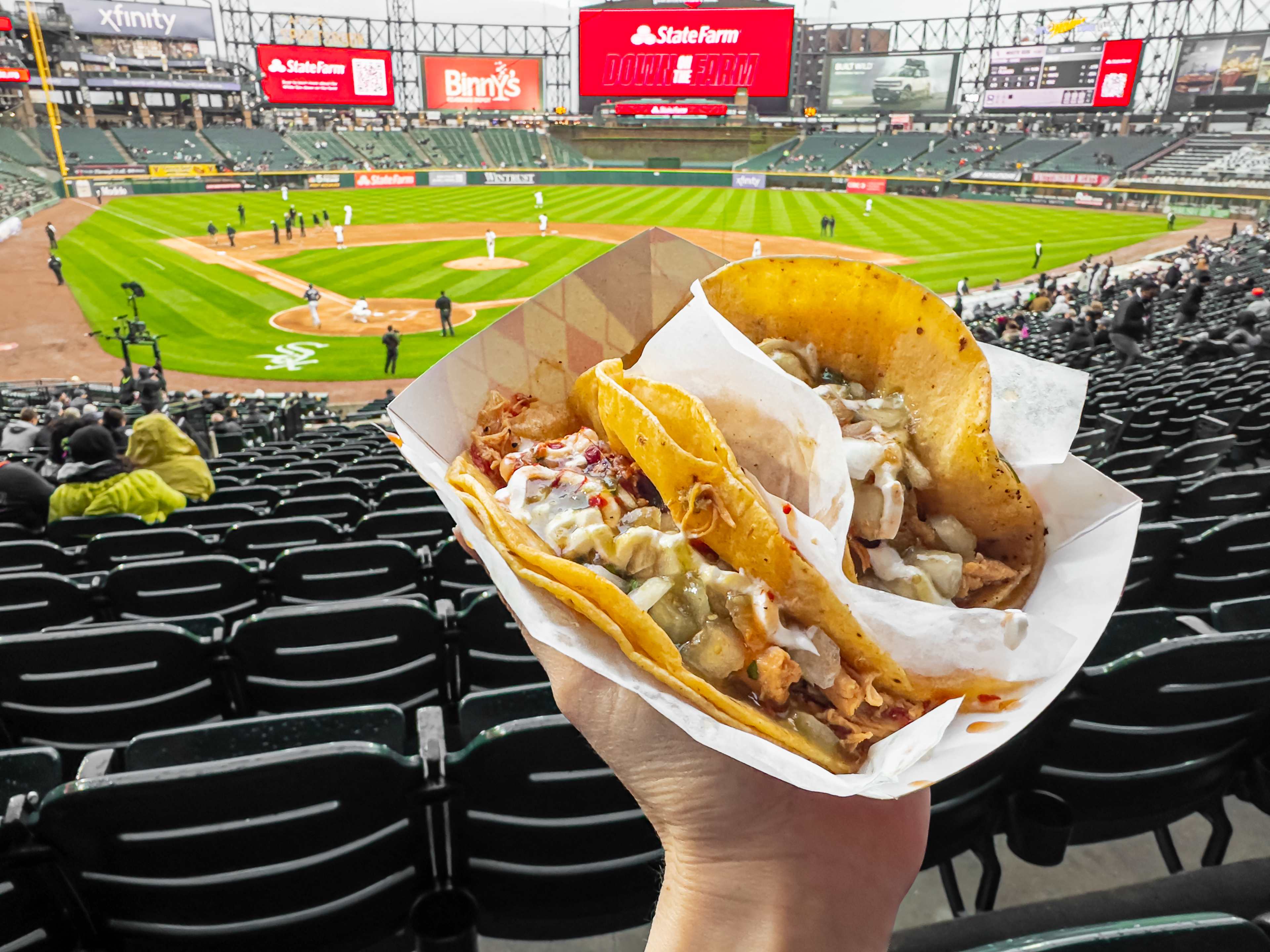 Tacos held up in front of a baseball diamond