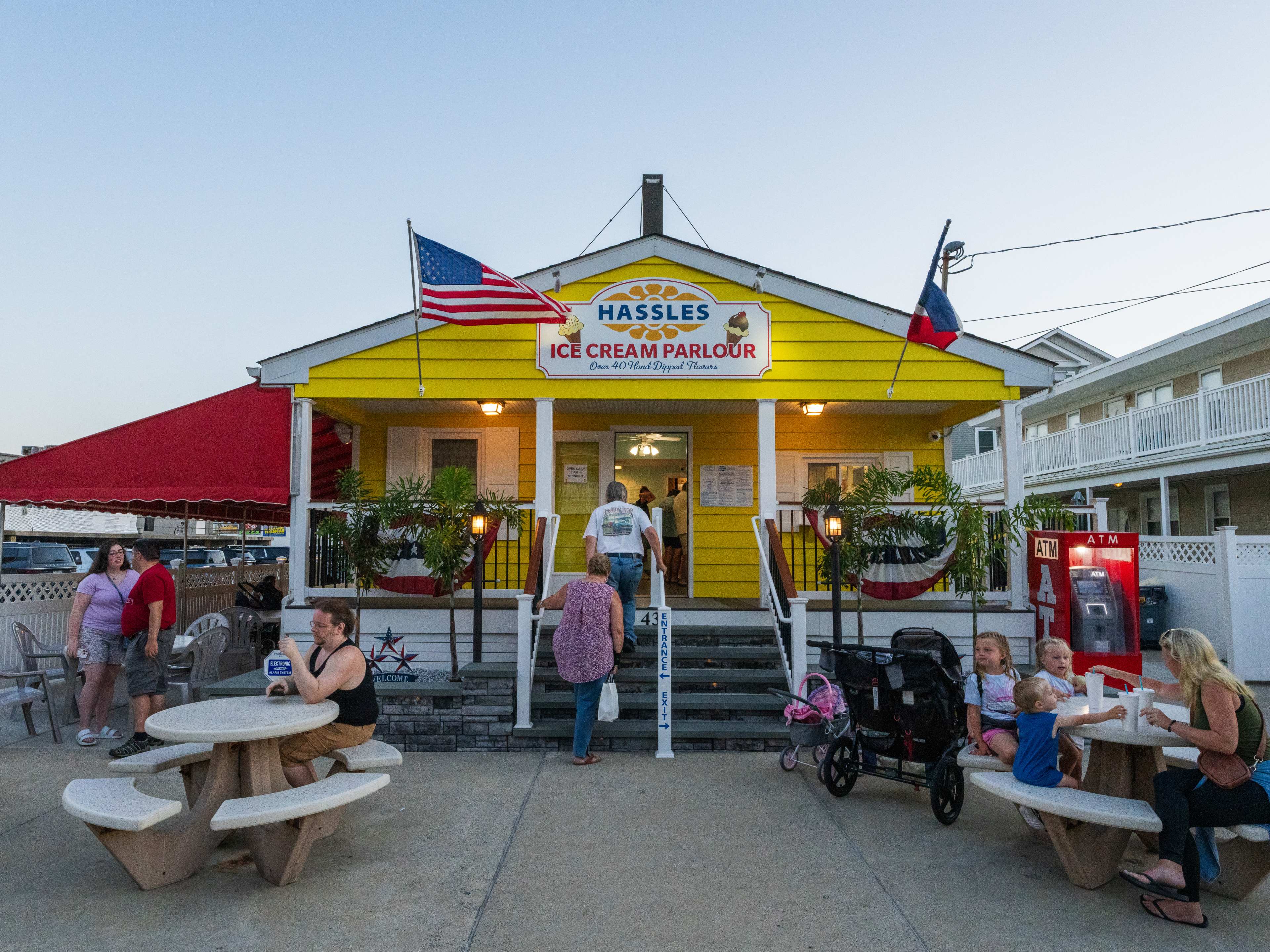 Colorful exterior and entryway with yellow paneling, a red awning, and picnic tables for guests.