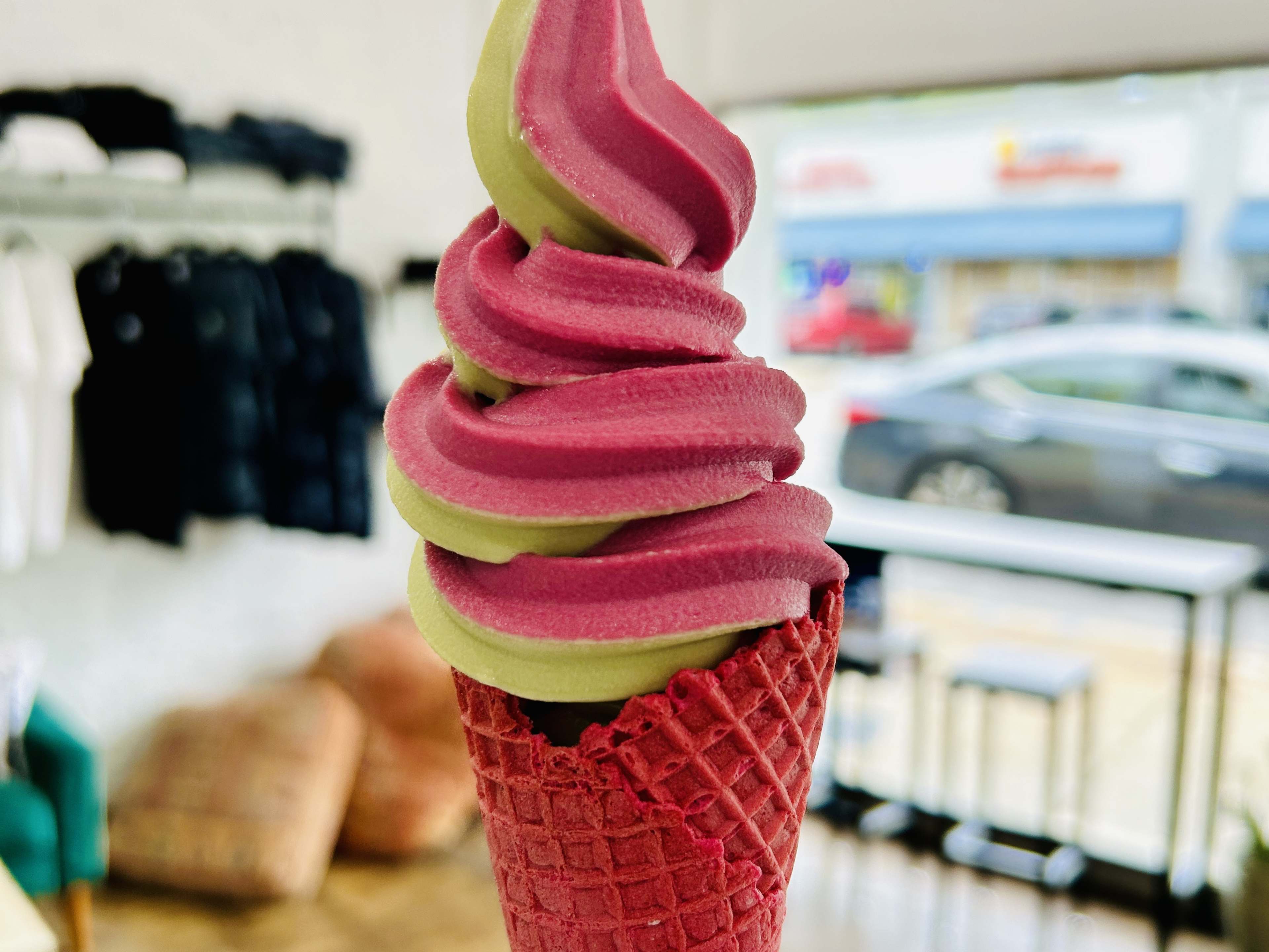 Pink and green ice cream in red waffle cone.