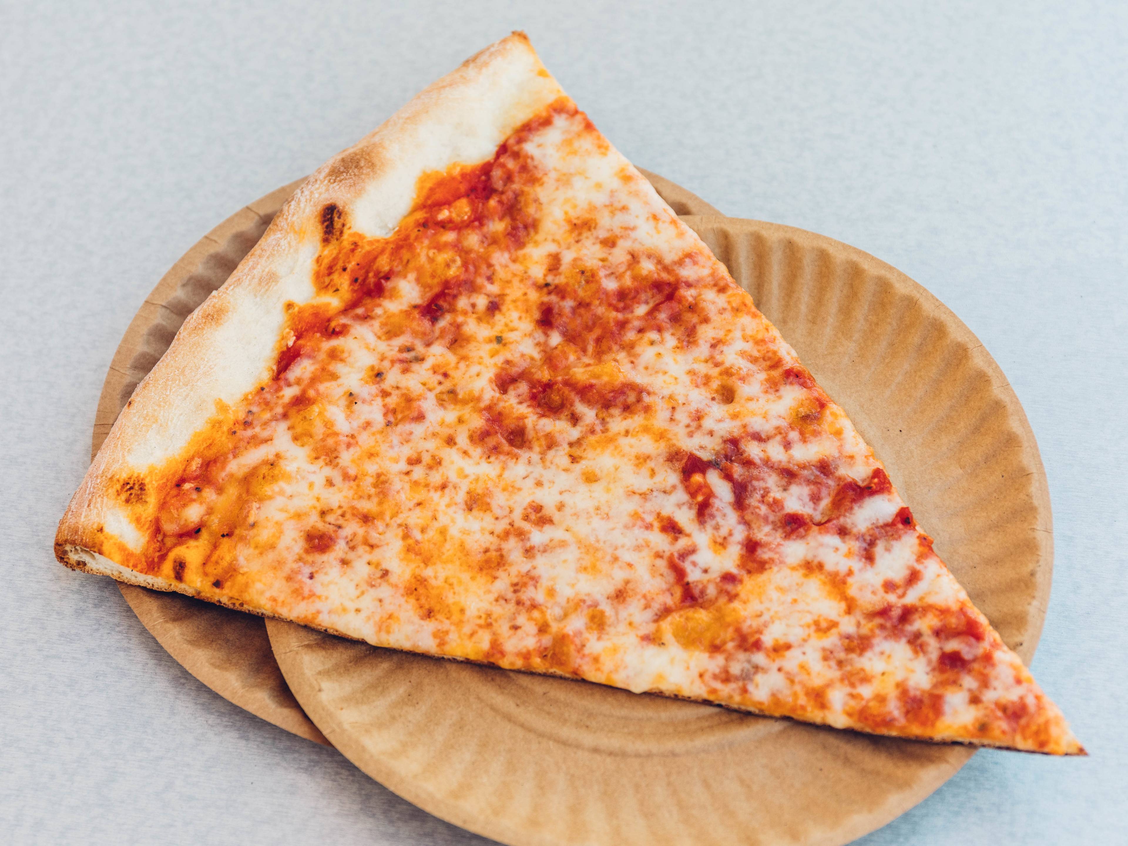 The Original South End Pizza cheese slice on a paper plate