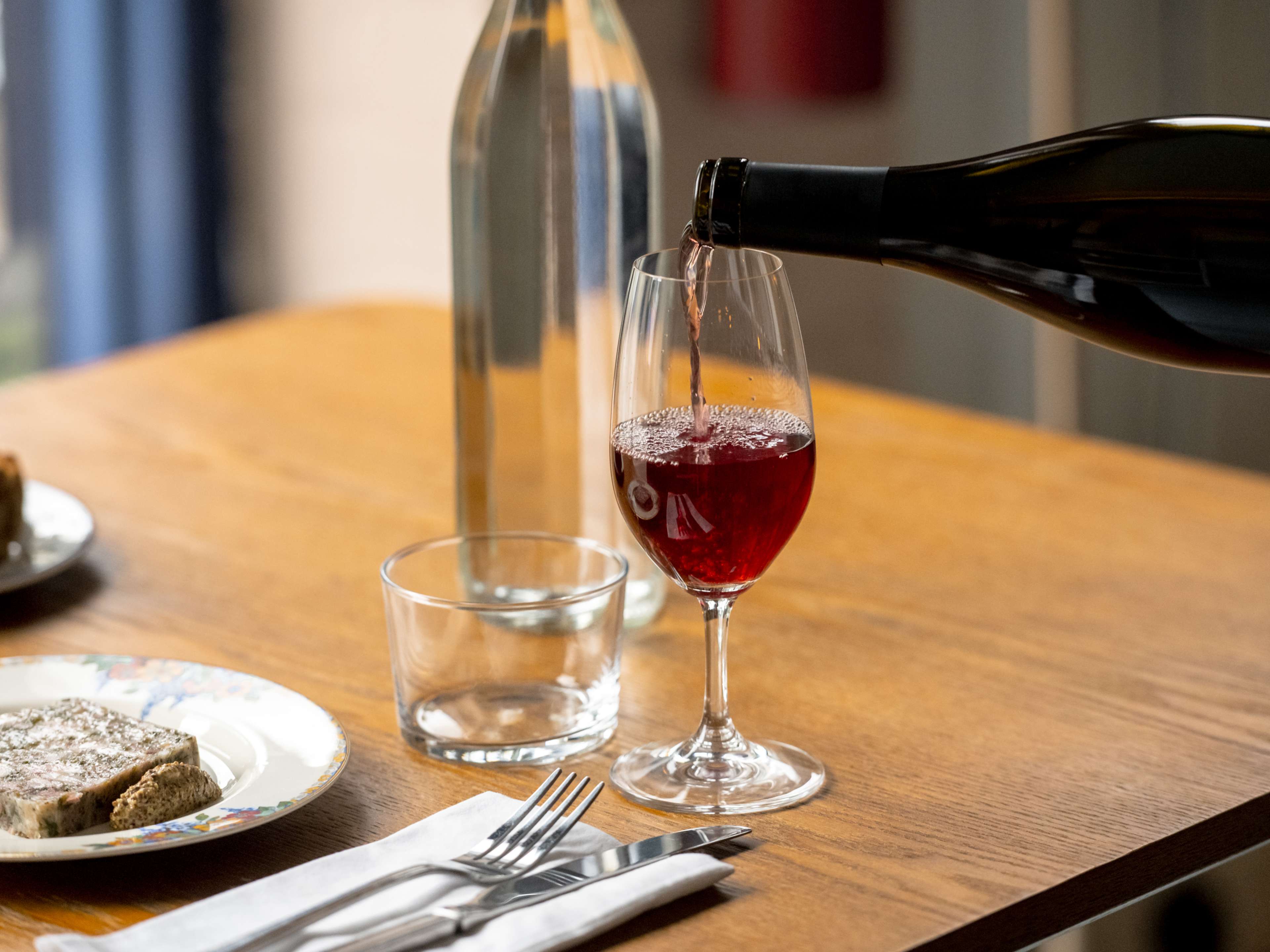 A bottle pouring red wine into a glass.