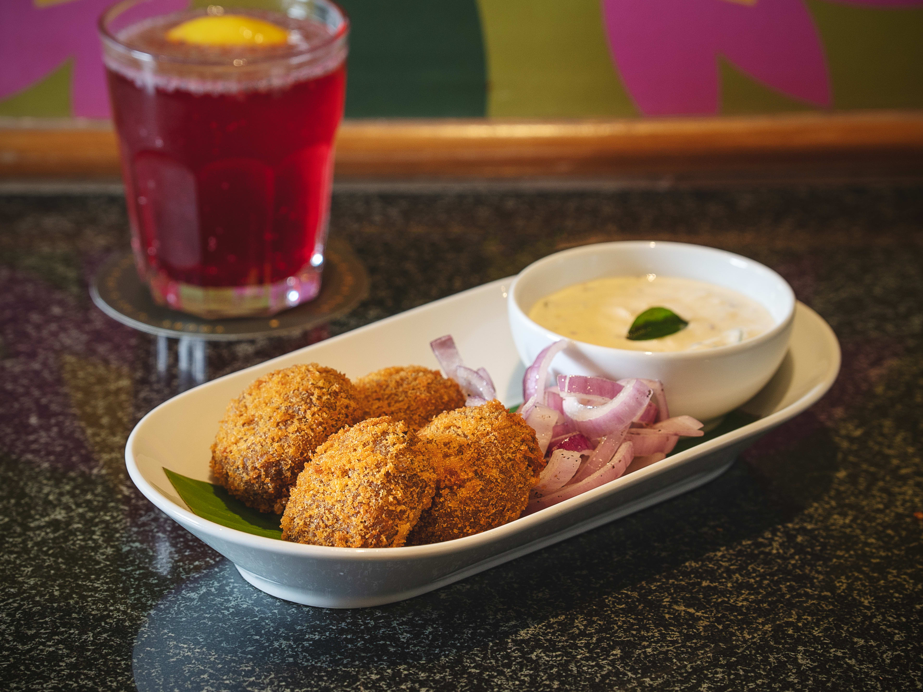 Slow-cooked Madurai mutton cutlets with dipping sauce and red cocktail at Kari Apla