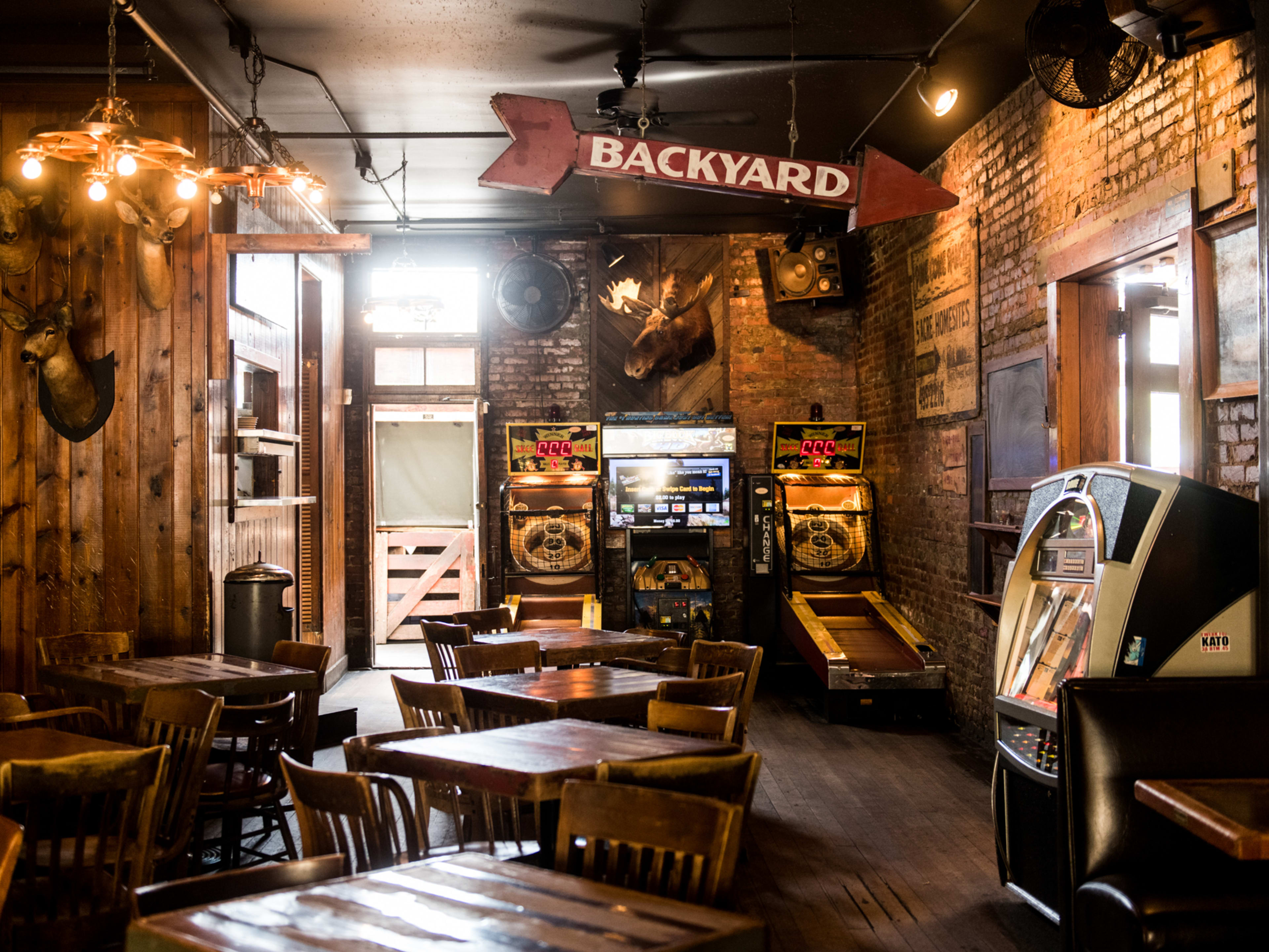 bar dining room with exposed brick, Skee-Ball, wooden tables, and taxidermy