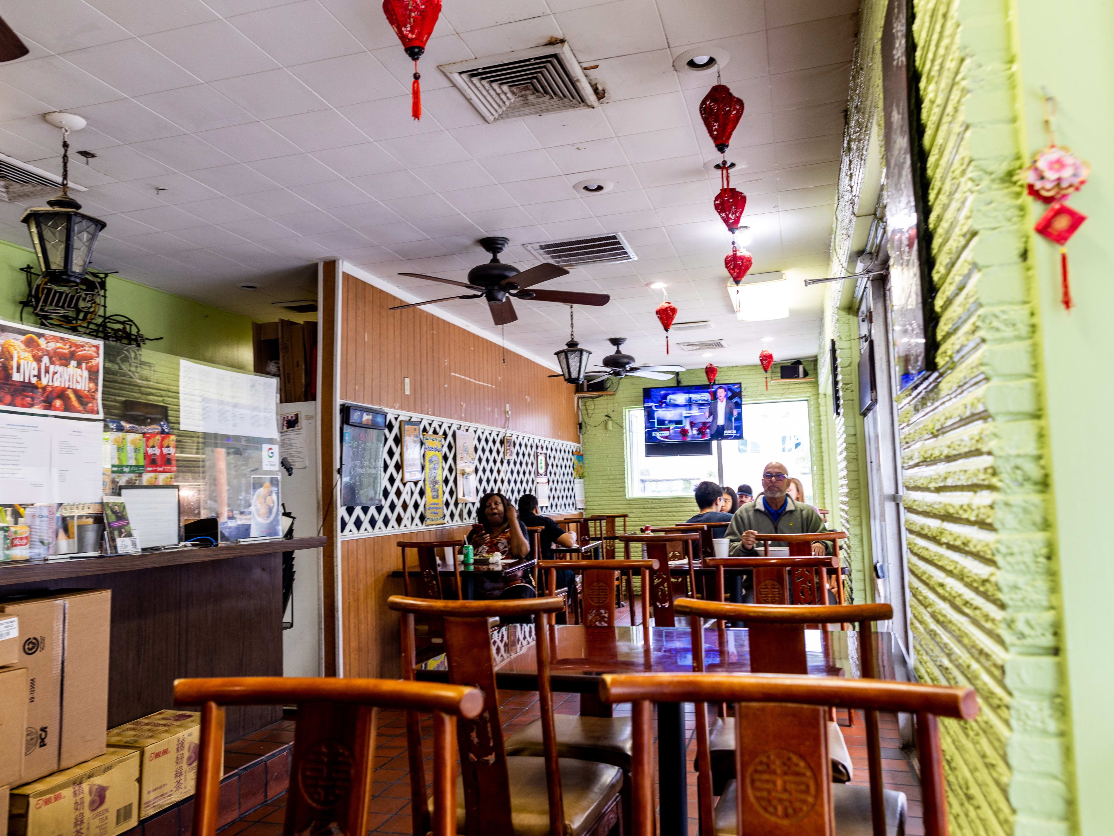 Vietnamese restaurant interior with wood panel and teal-painted walls, red lanterns on the ceiling, a small walk up counter window.