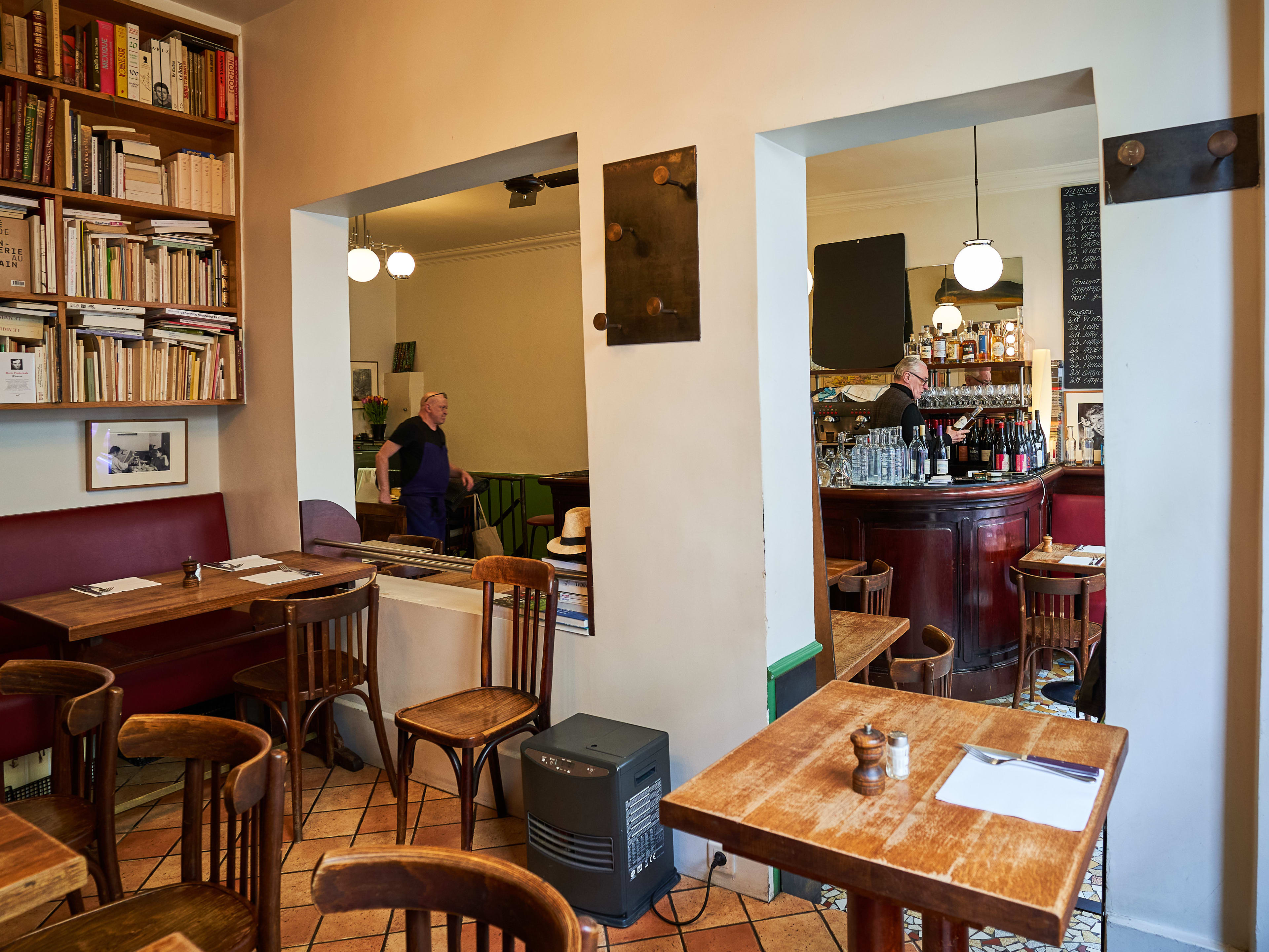 Interior dining room with wooden tables and red booths at Le Baratin