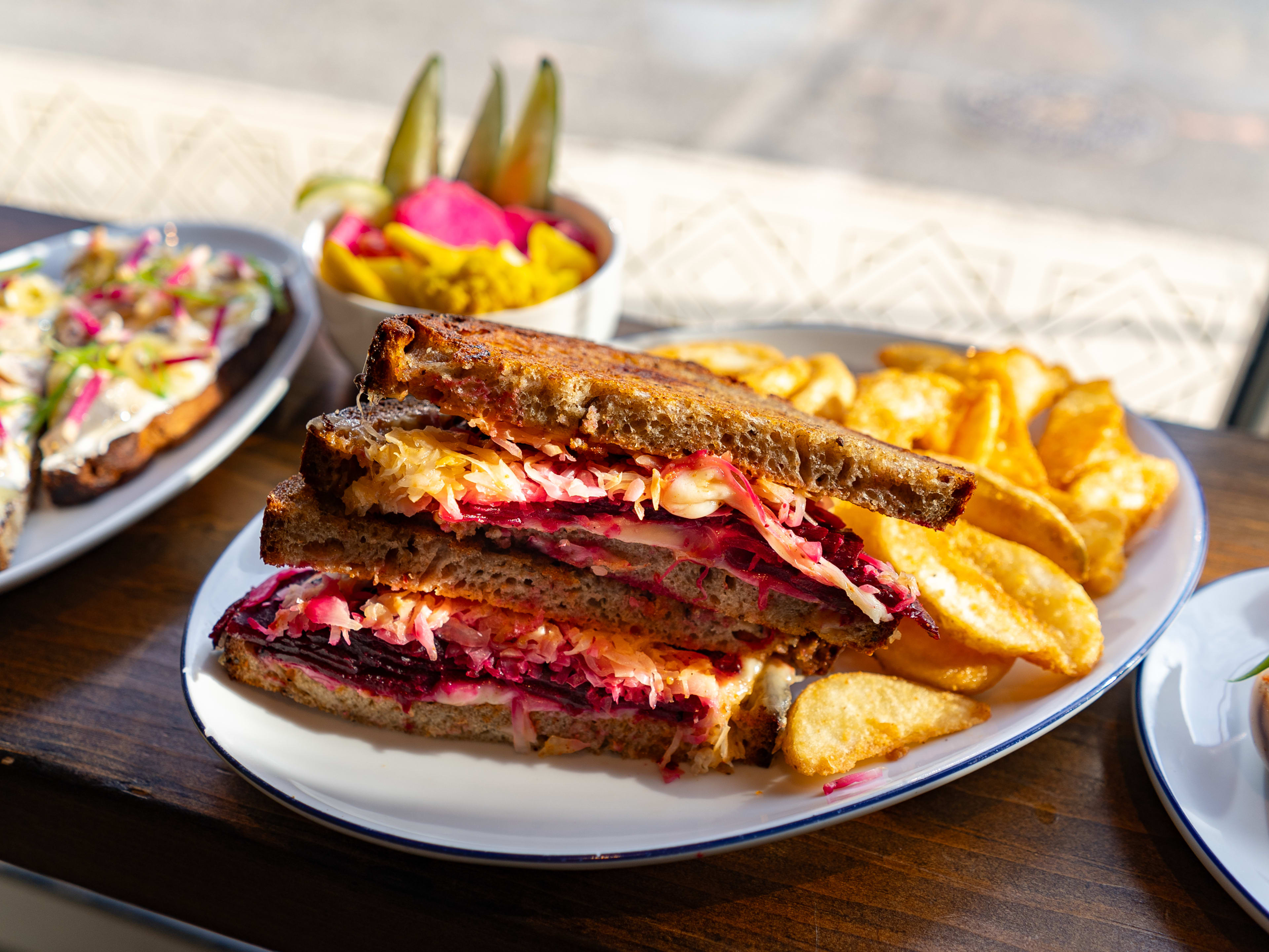 Beet pastrami sandwich on rye bread with side of potato chips at Lehrhaus