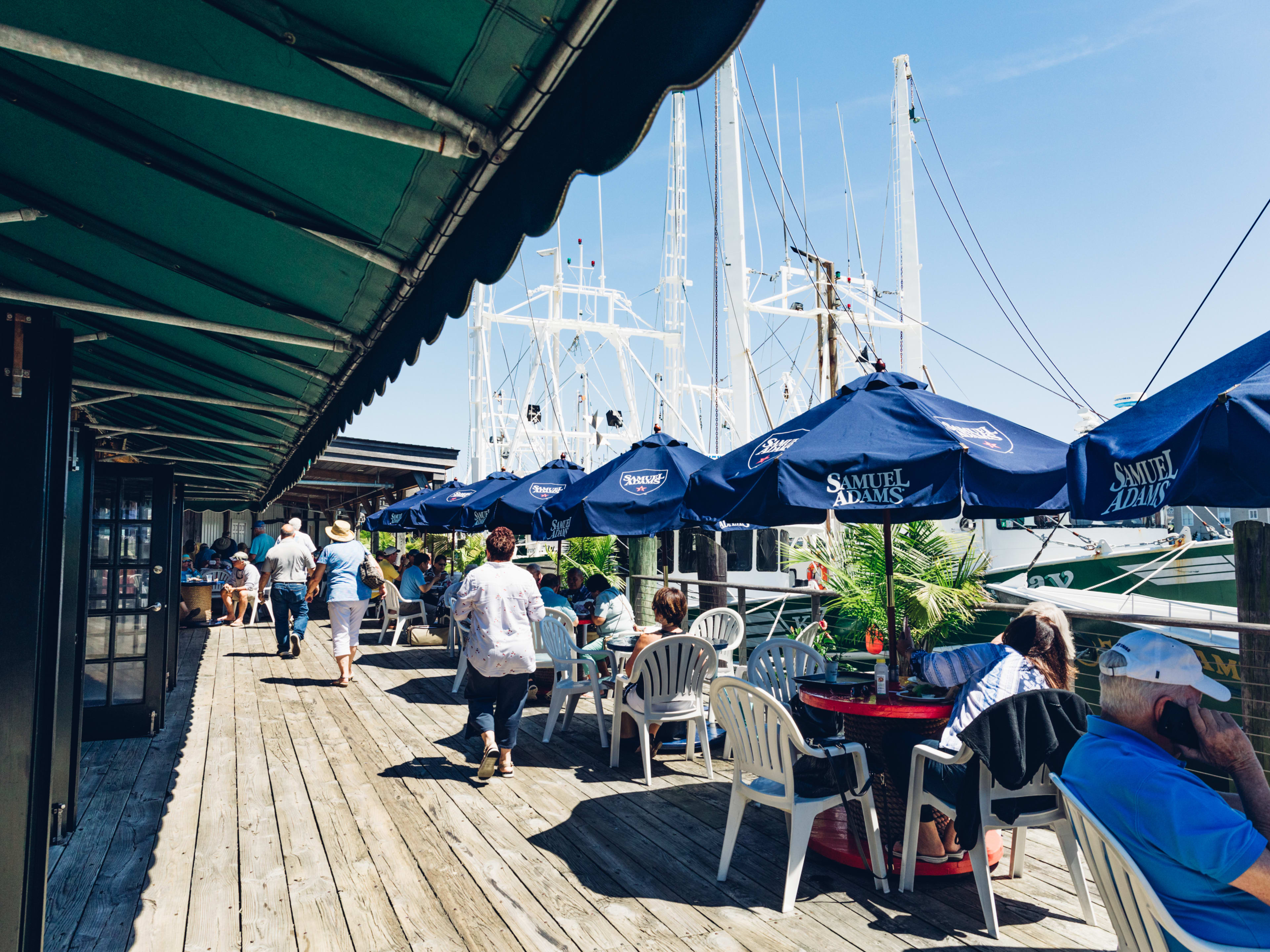 The Lobster House outdoor dining with a view of the water with boats and people seated at outdoor tables with umbrellas