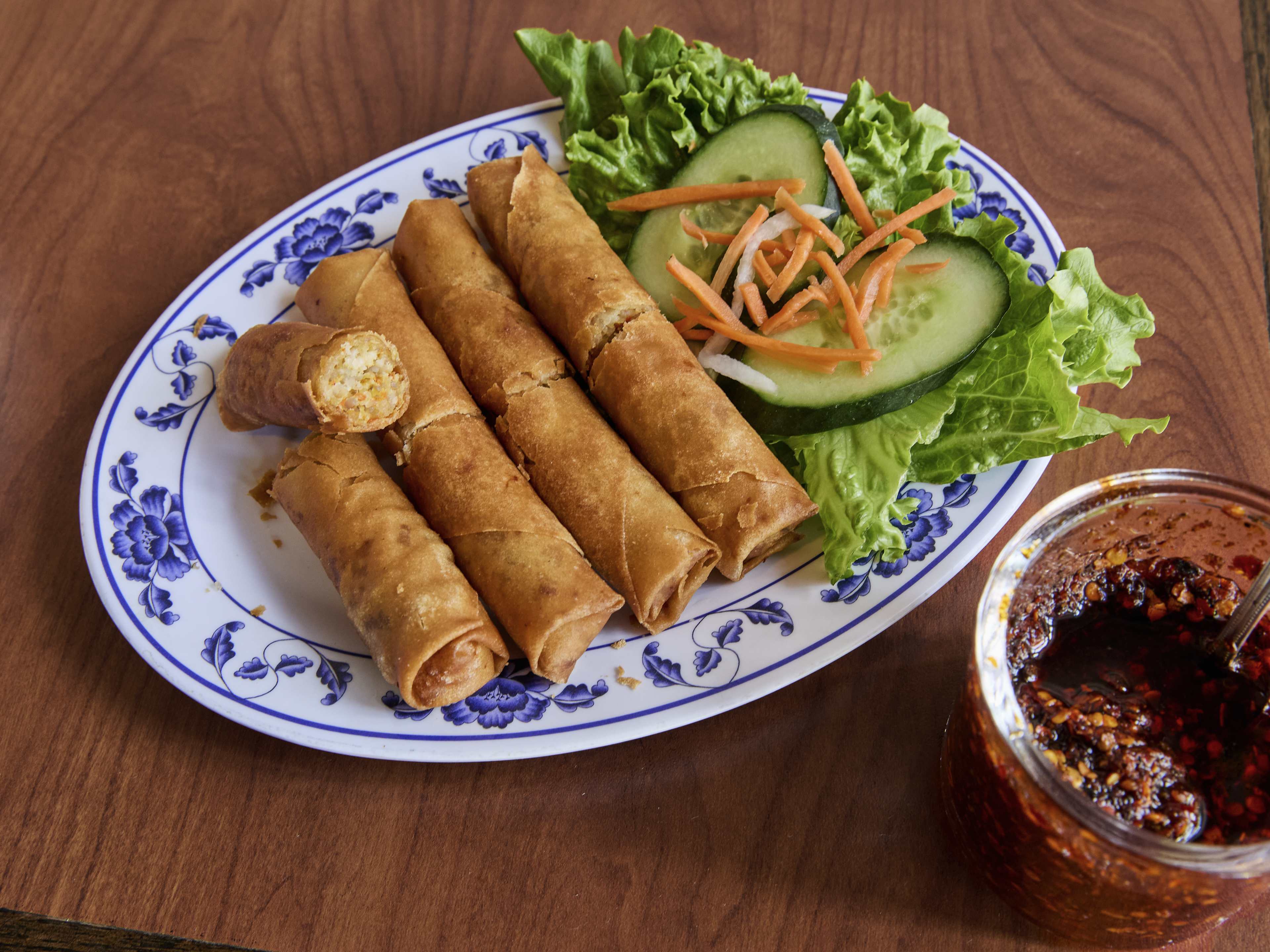 crispy fried eggrolls served next to small salad of cucumbers and carrots