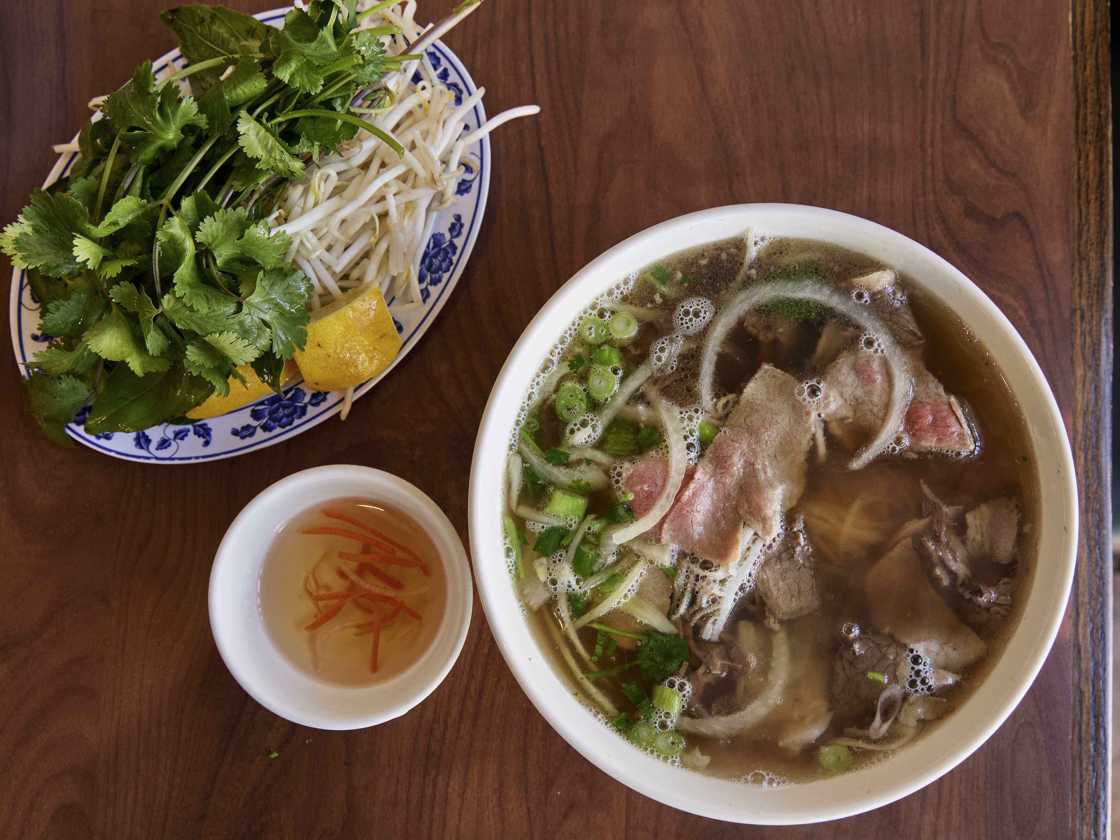 pho soup with meat green onion and plate of garnish