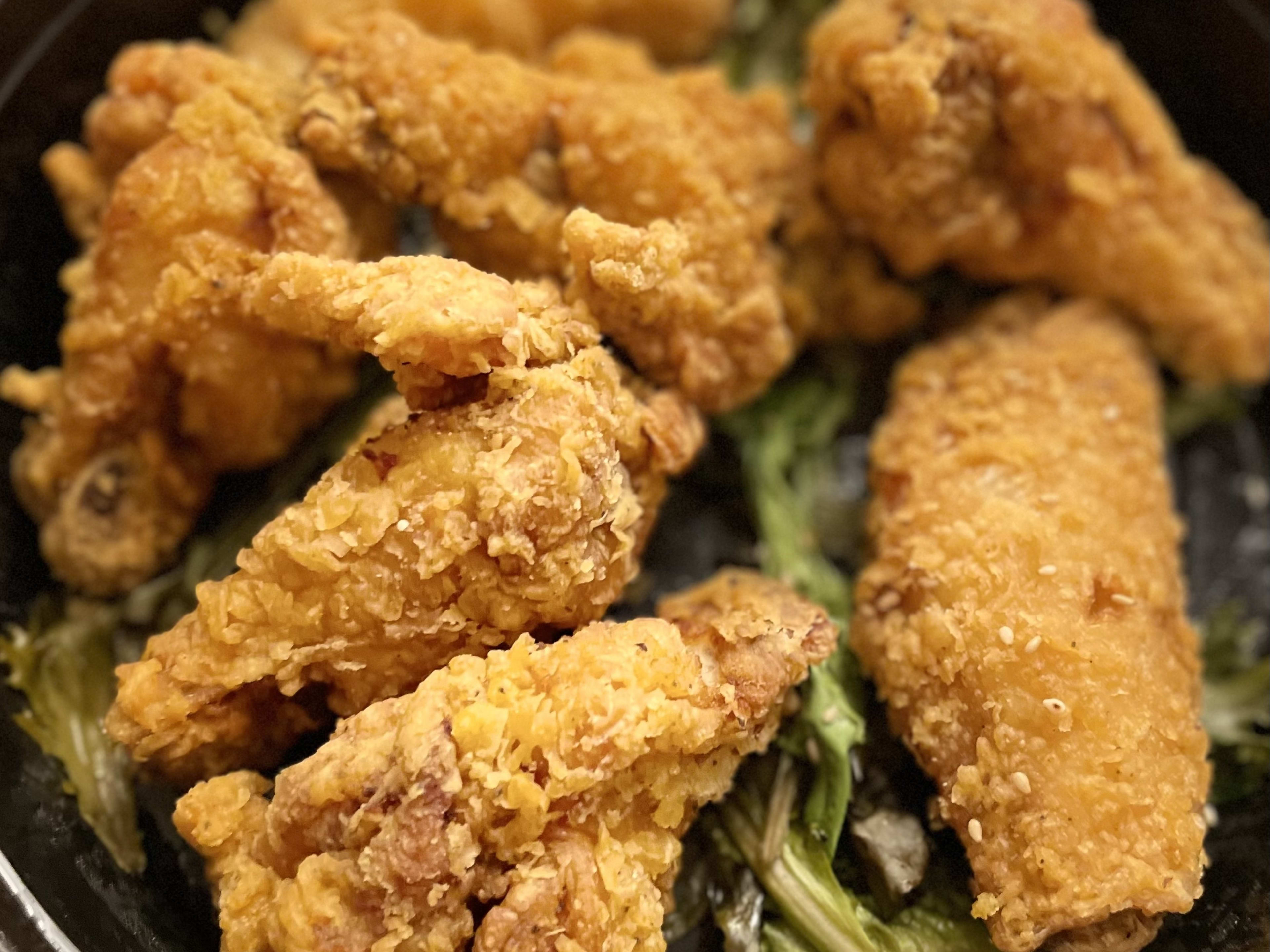 Korean fried chicken in a plastic black serving dish.