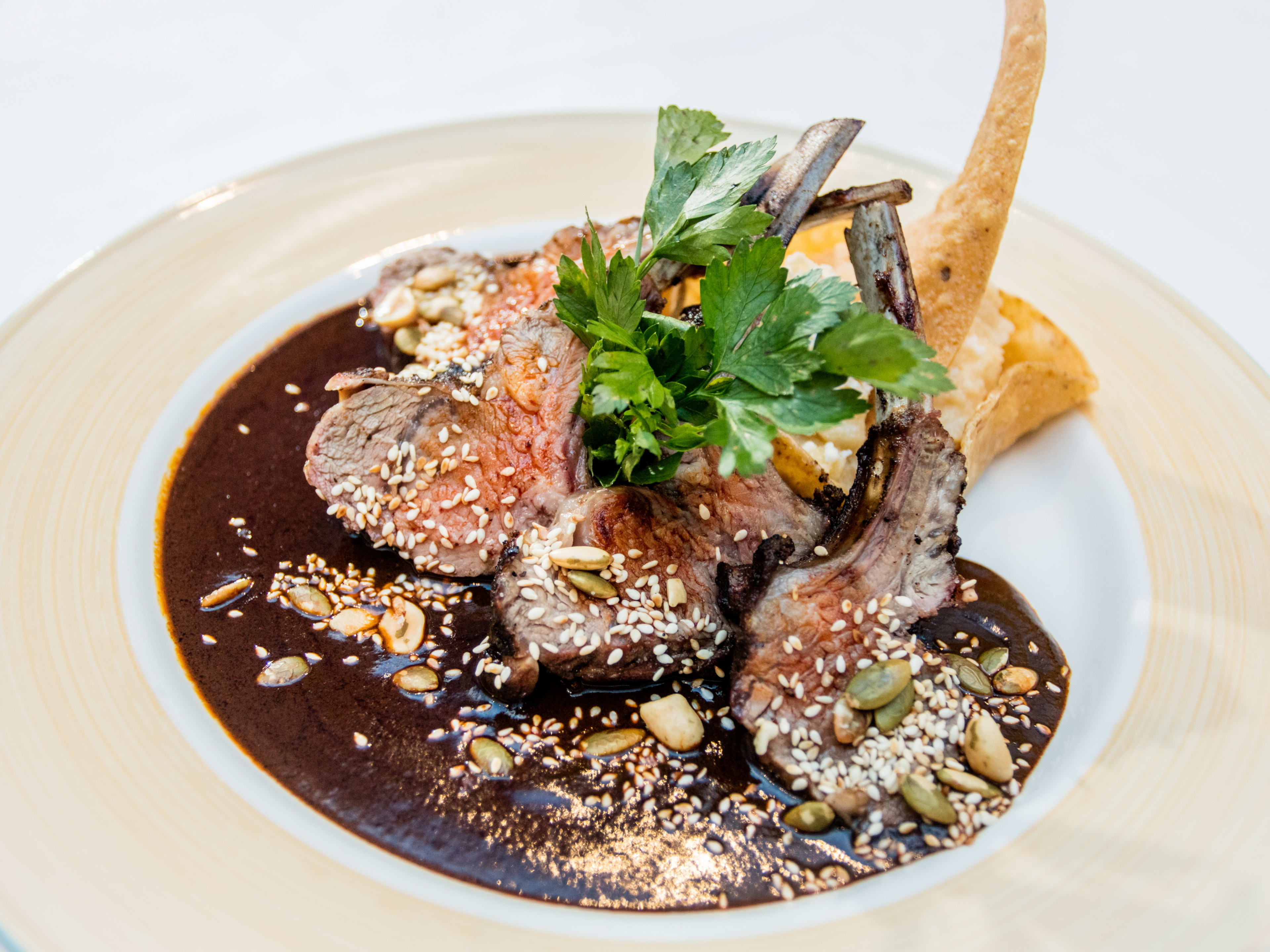 A plate with lamb chops and black mole.