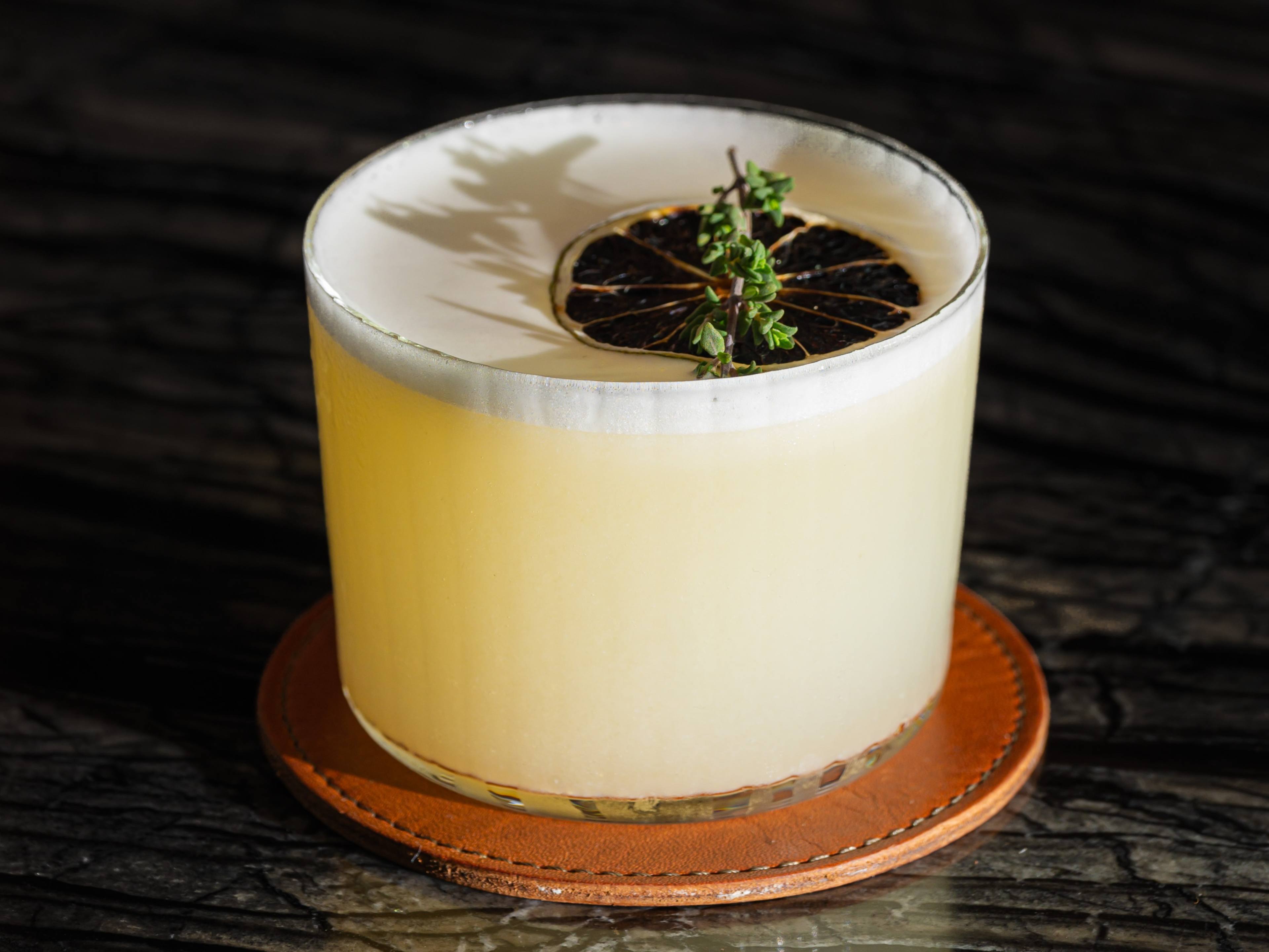 Andiron margarita with a fluffy rim of egg white foam topped with a dehydrated lime slice