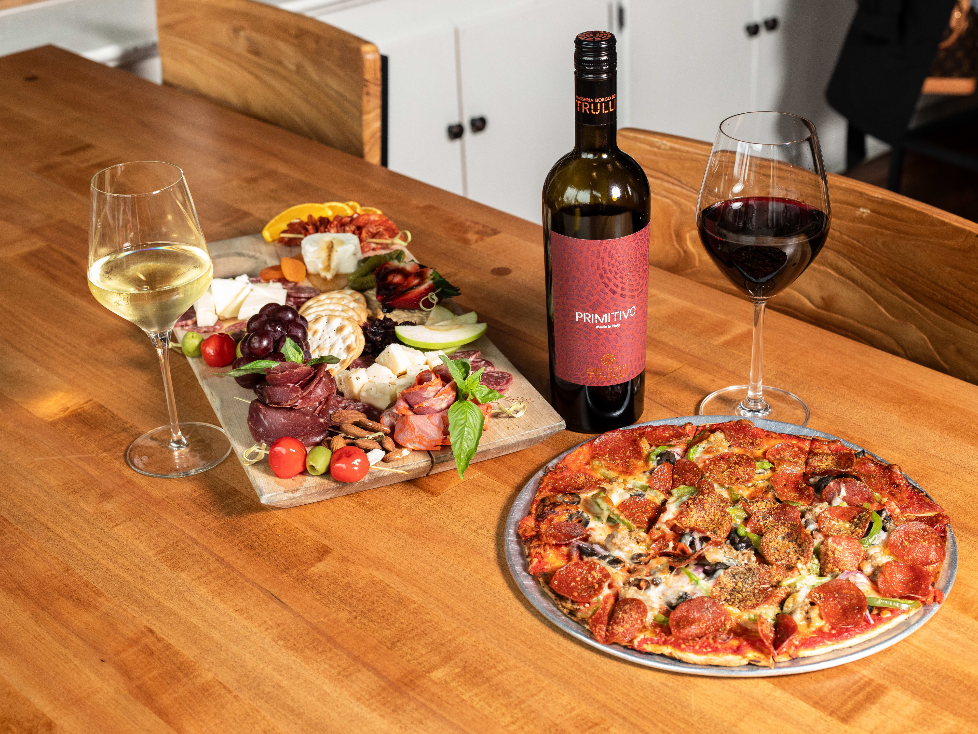 Sicilian Pizza and Charcuterie Board paired with glasses of red and white wine.