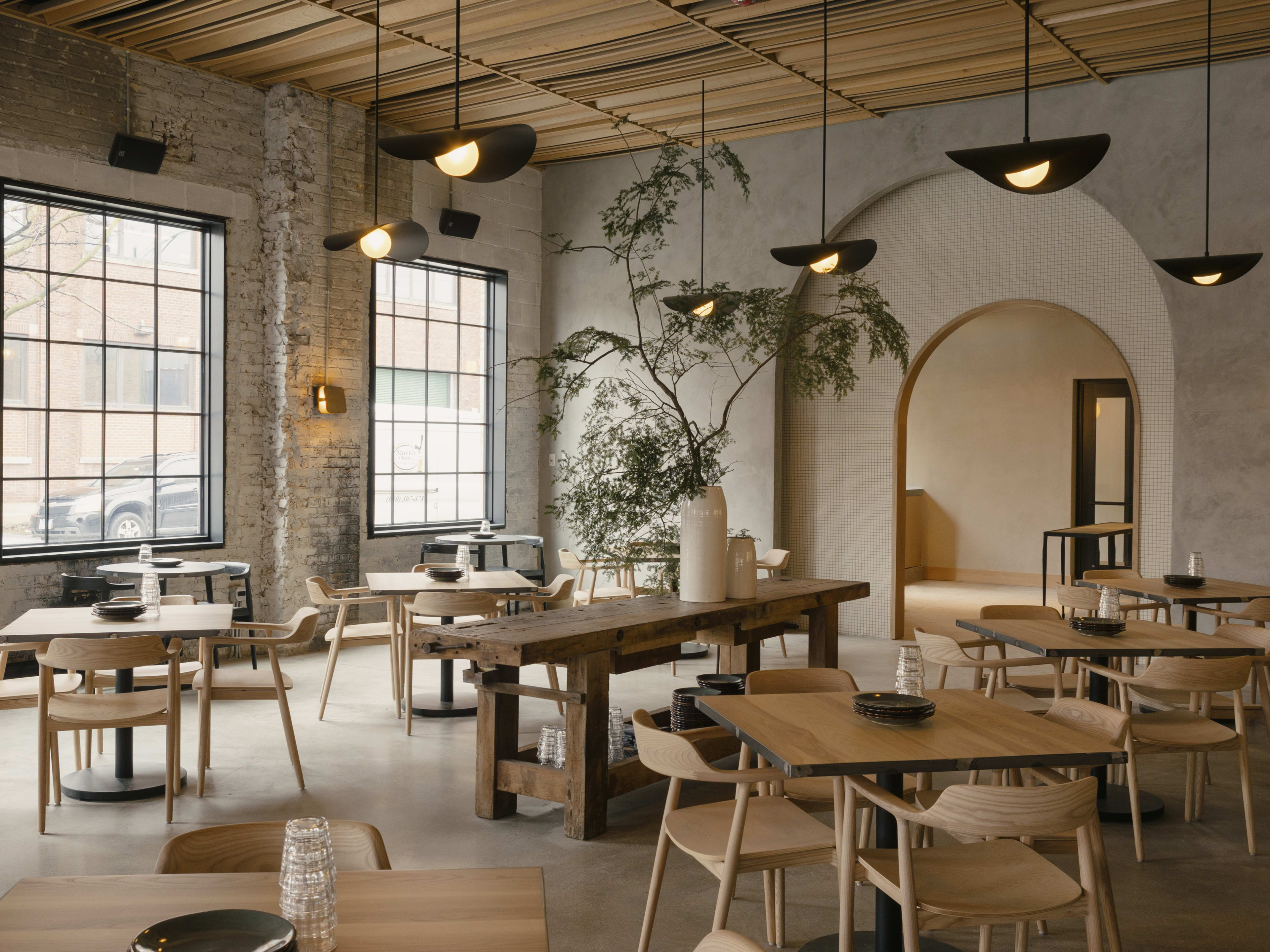 The dining room at Maxwells Trading with wooden tables and large windows on the left side