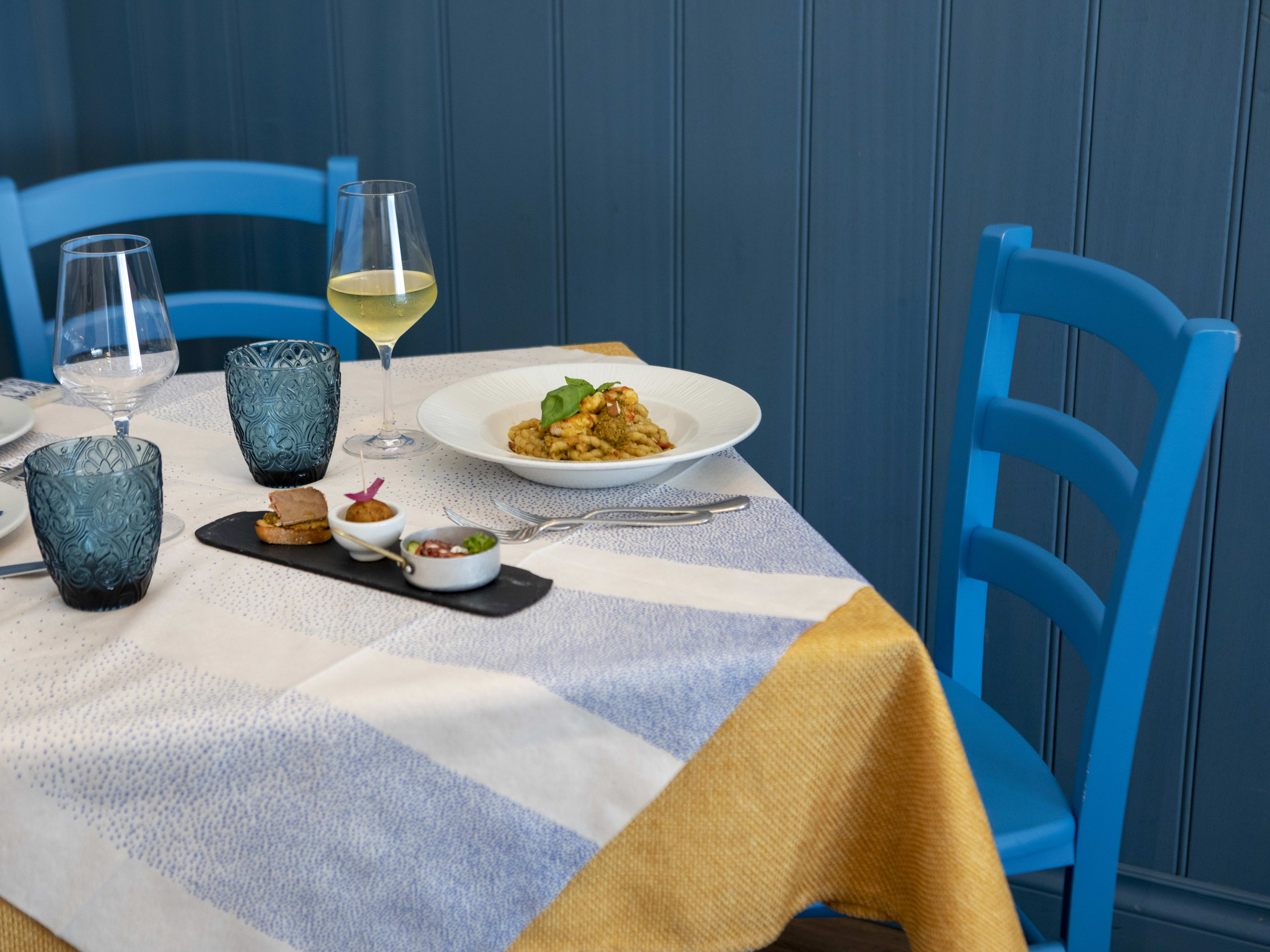 Pasta dish with small sides and glass of white wine at Osteria Mercede