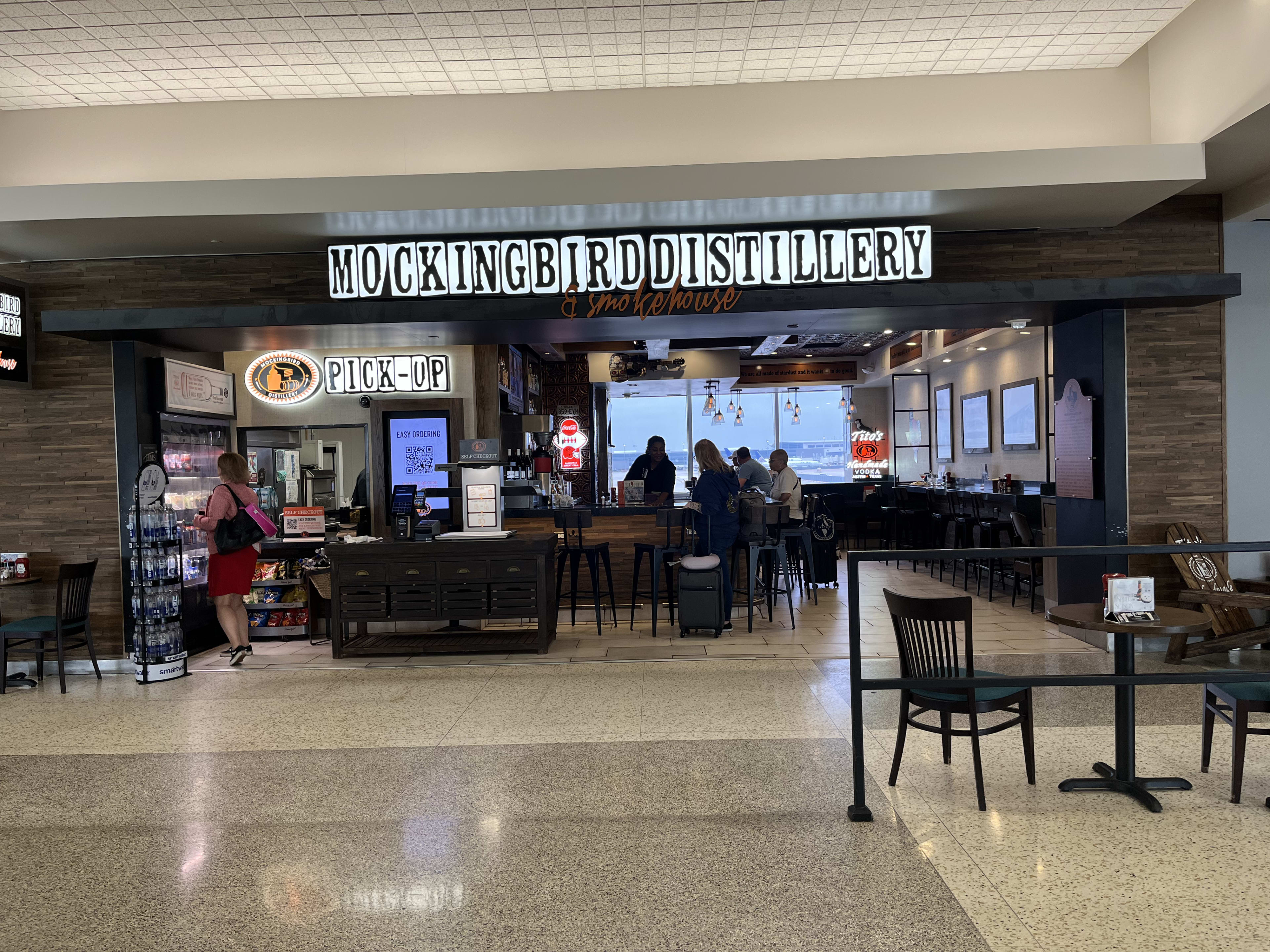 photo depicts the exterior of mockingbird distillery & smokehouse, which is the bar area and a counter with individual stools