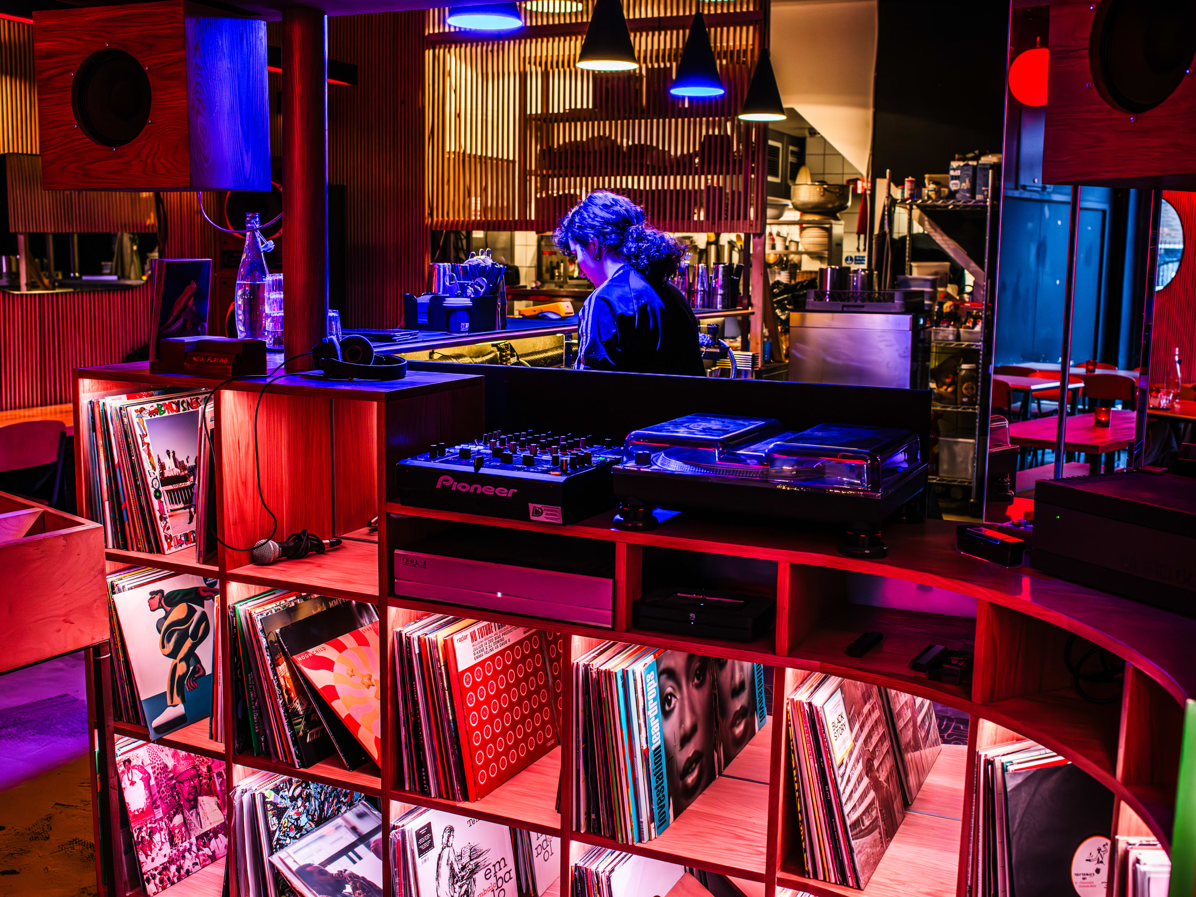 The DJ booth at Moko with decks and records with shelving underneath.