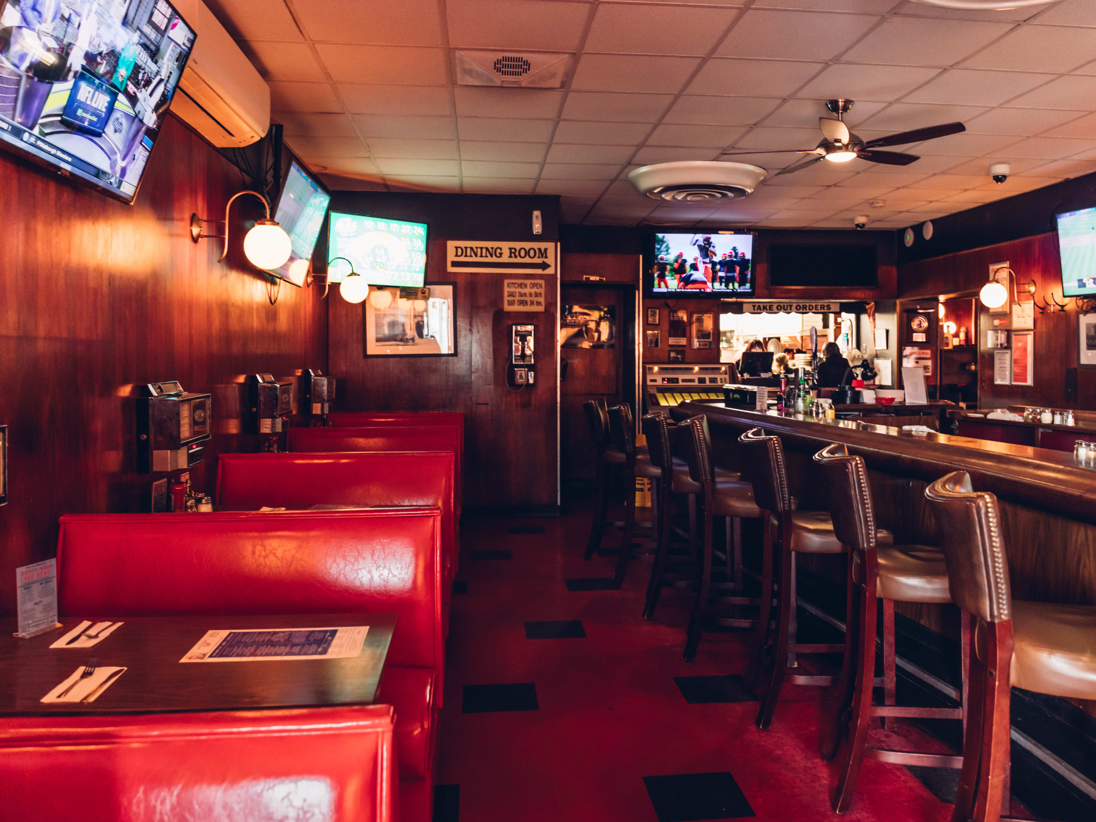 Tony's Baltimore interiors with red booth seating on the left and high top stools at the bar on the right