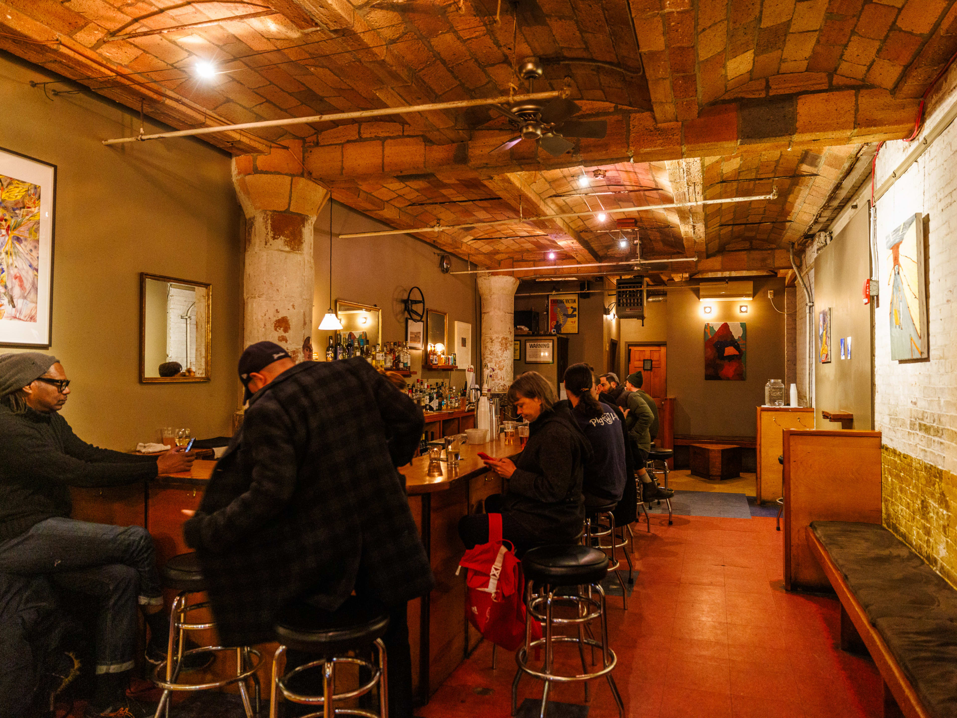 68 Jay St Bar interior with wood ceiling, benches on the right, and people seated around the bar on the left