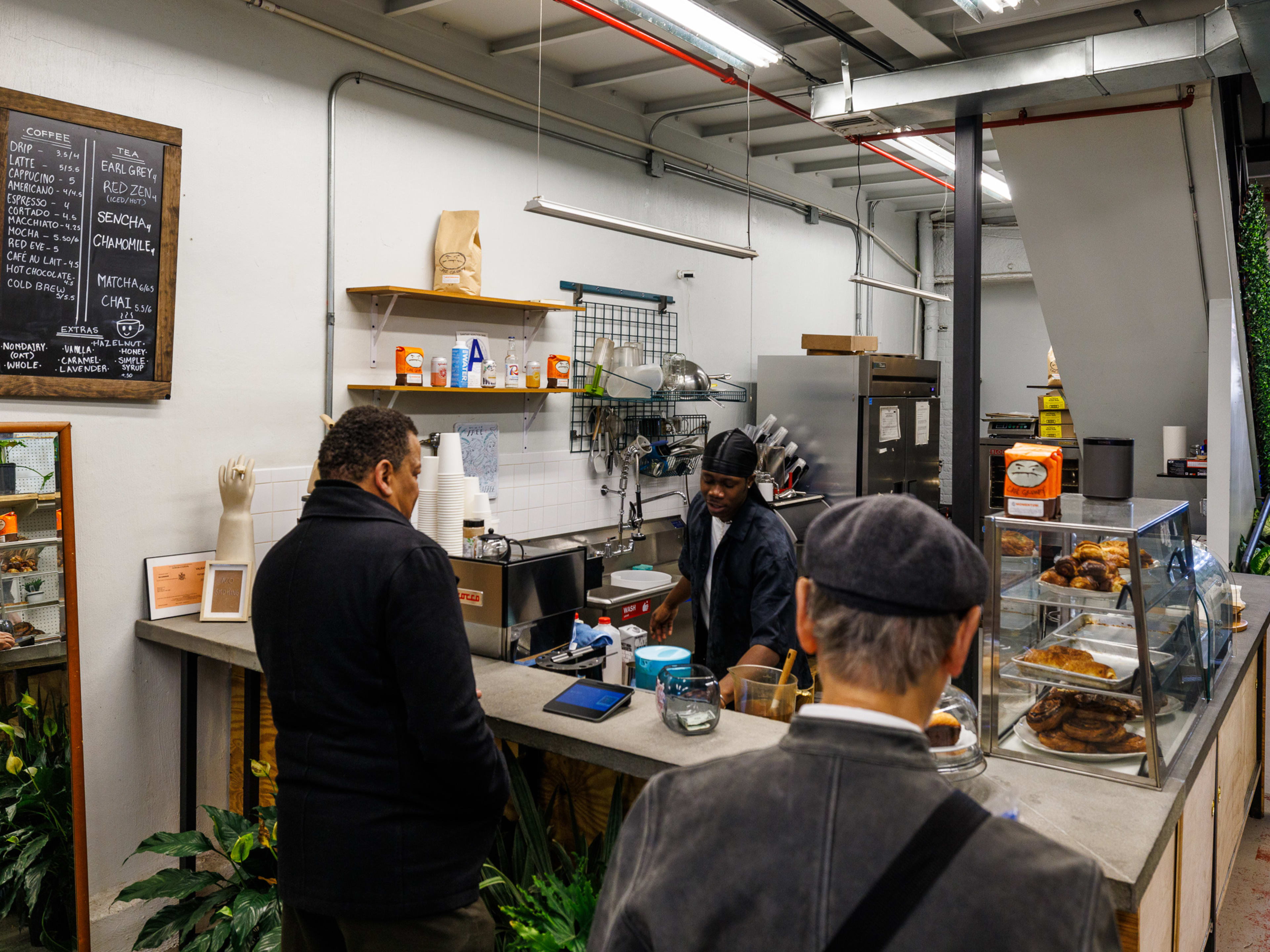 9Tails interiors with customers ordering at the counter and pastries in a display case to the right