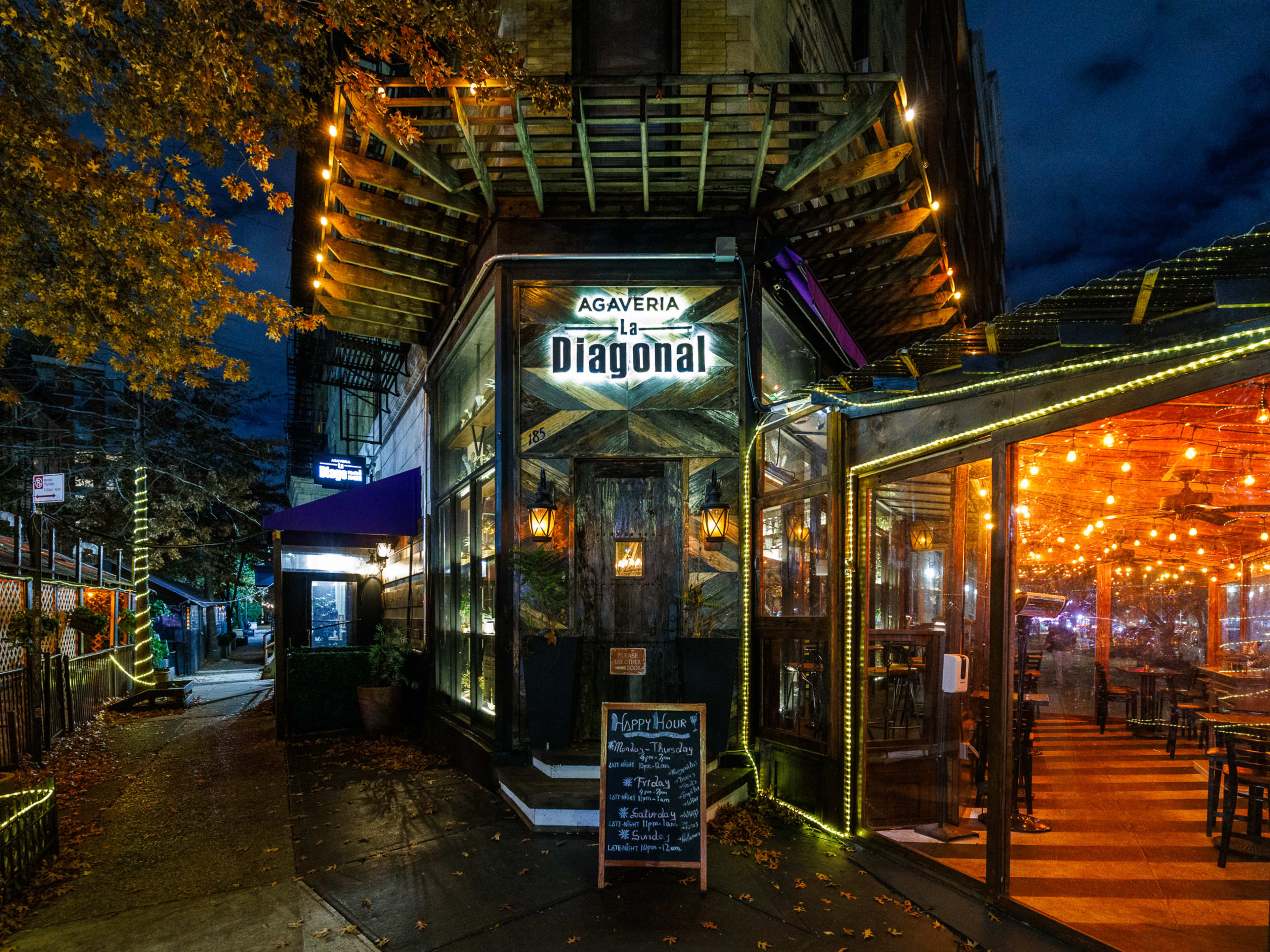 La Diagonal exterior at night with outdoor seating to the right with string lights hanging on the ceiling