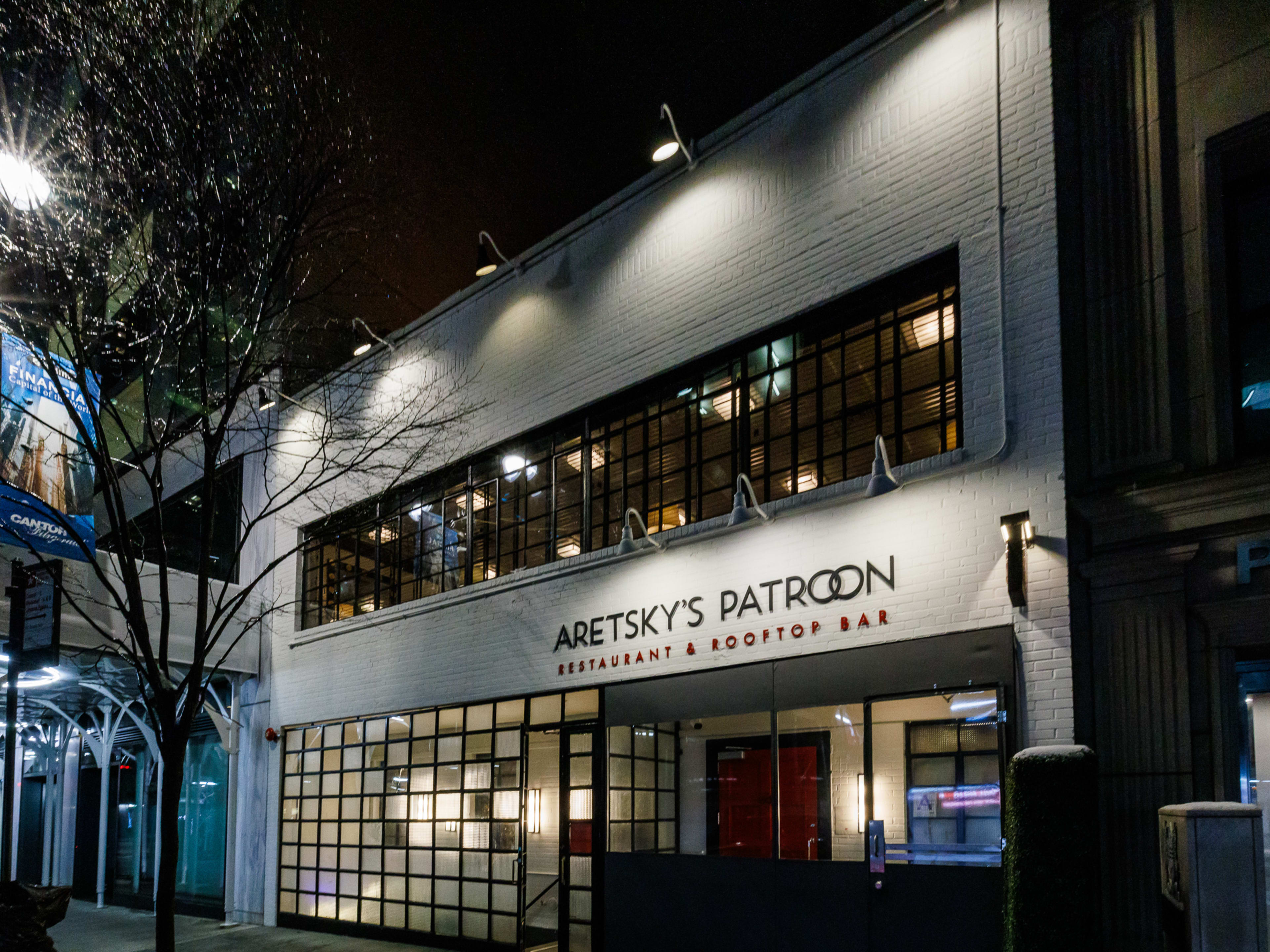 The Roof At Aretsky gray brick exterior with spotlights aimed at the restaurant sign at night