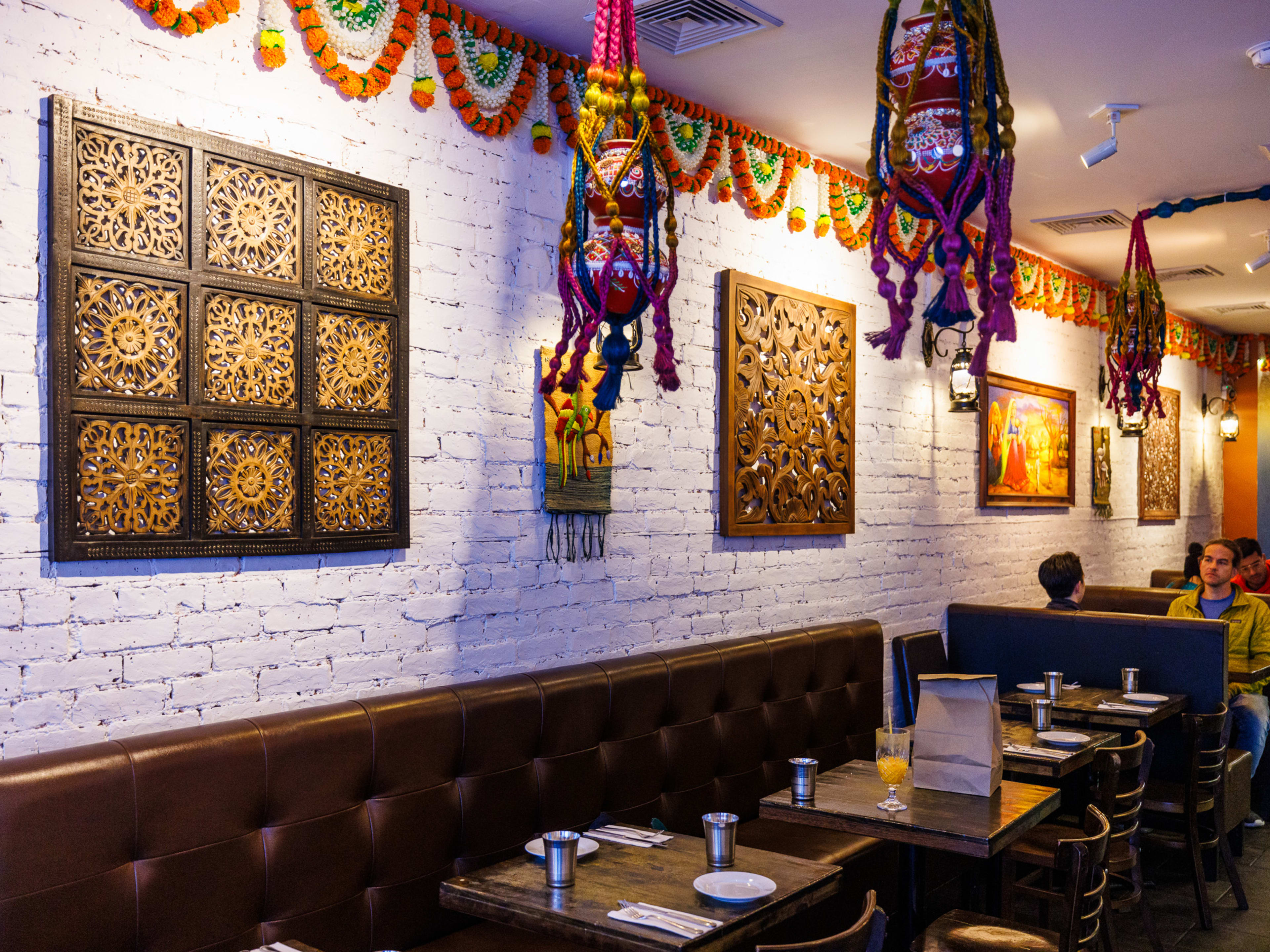 Interior at Atithi Indian Cuisine with brick walls, booth seating, and hanging lanterns