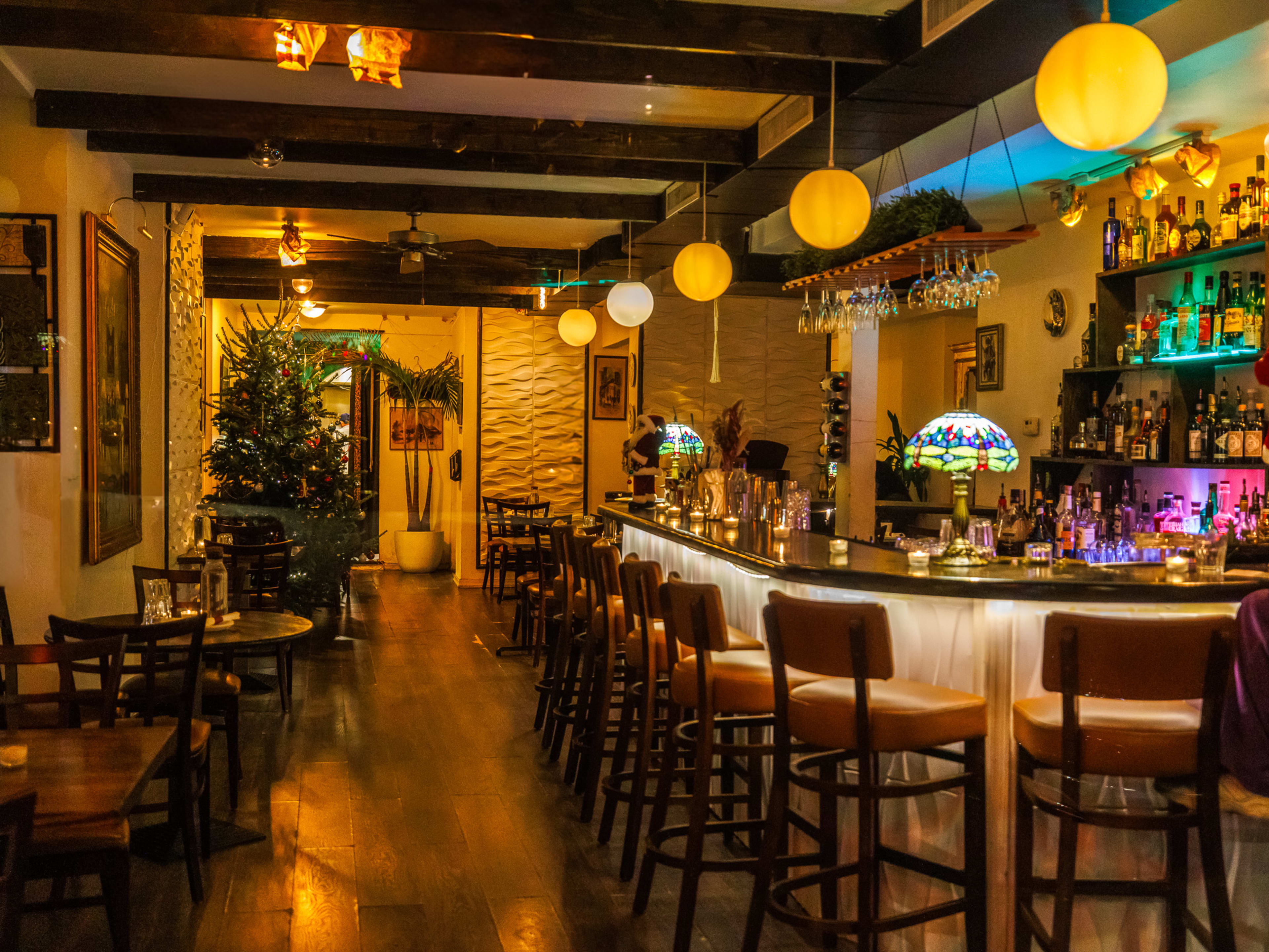 Black Iris interiors with vintage glass lamps on the bar, bar seating, wood tables on the left, and christmas decorations