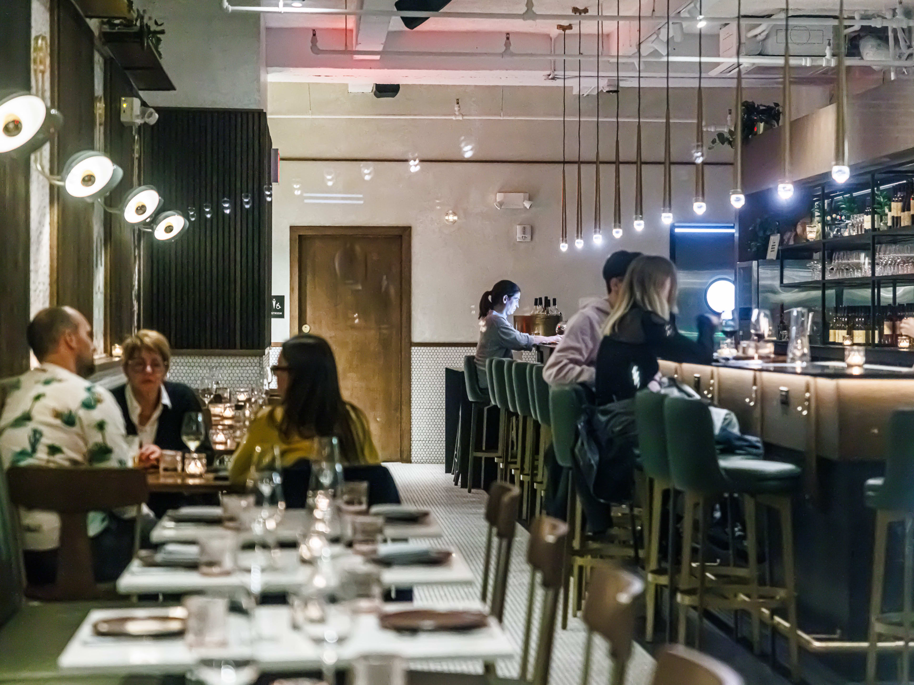 Interior of Brooklyn Winery at night with bar seating and booth seating