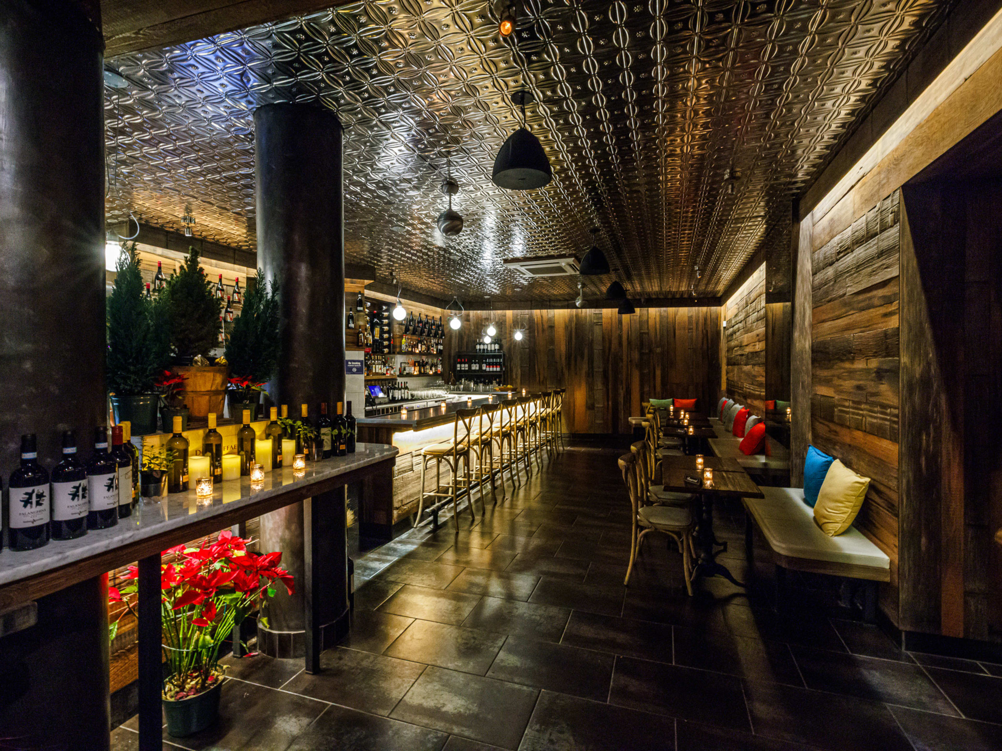 C. Di Palo Wine Bar interiors with dim lighting, wood paneled walls, candles on the bar and tables, and wine bars lining the counter on the left