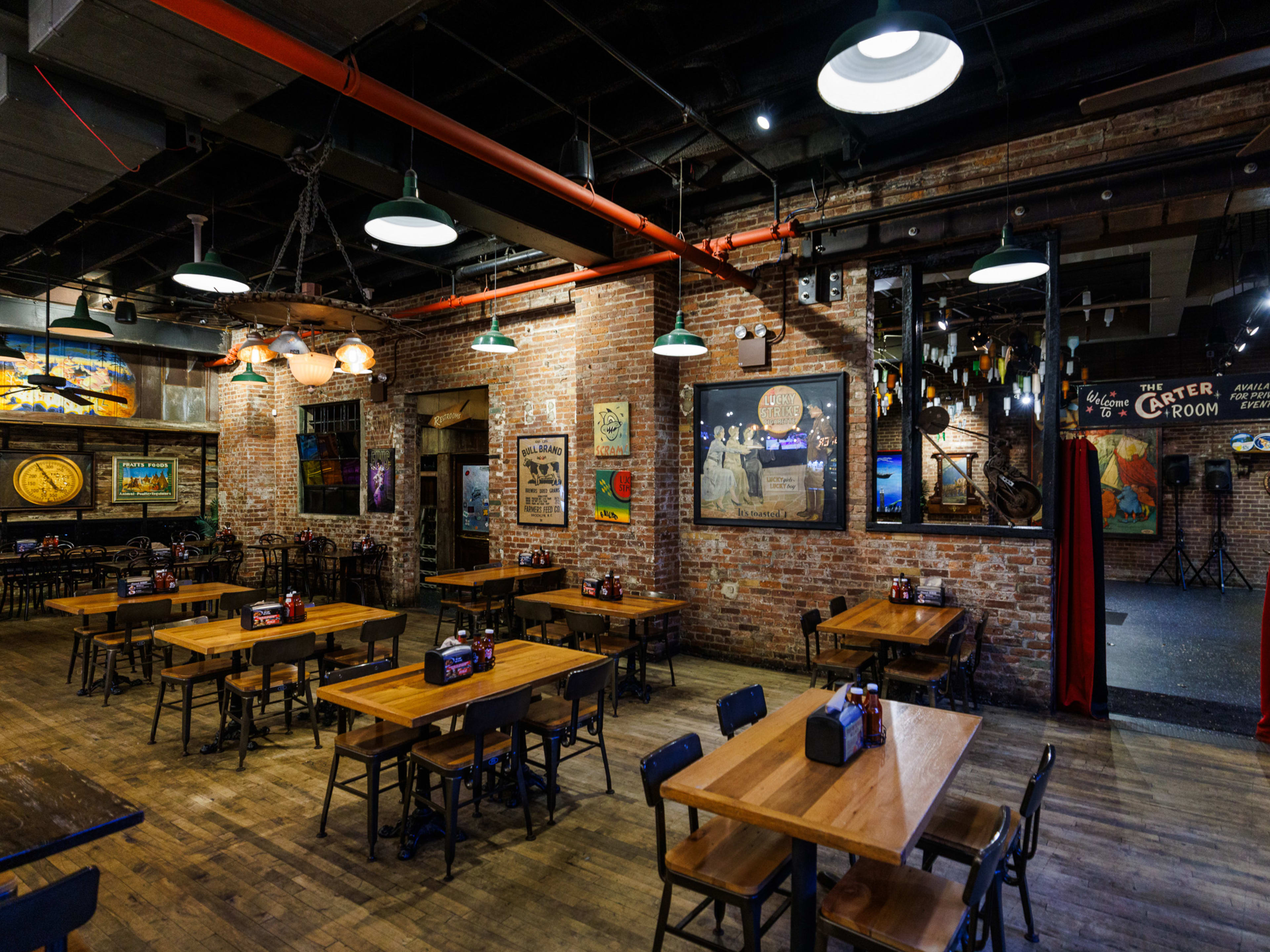 Dinosaur Bar-B-Que interiors with brick walls, framed art on the walls, and multiple square wooden tables