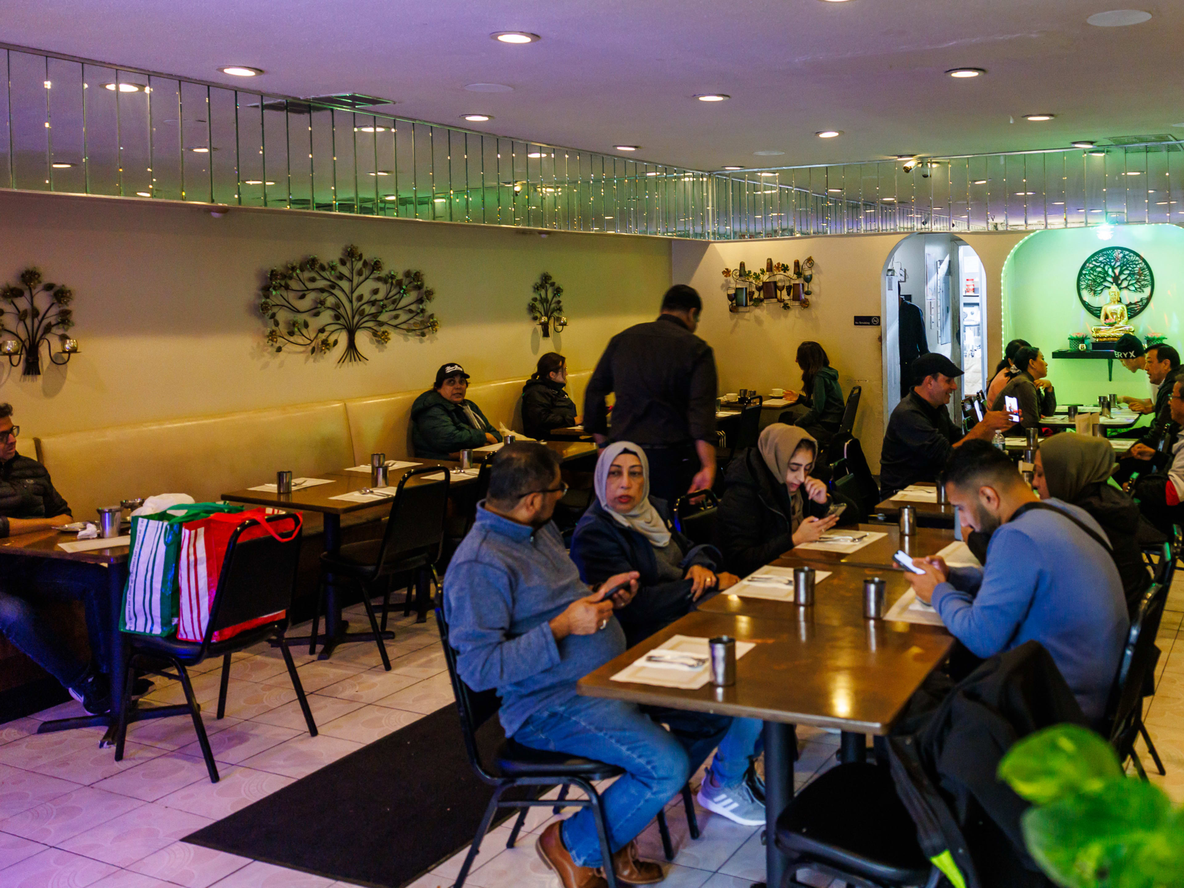 Dosa Delight interiors with dim lighting, mirrors all around the edge of the ceiling, and people seated at wooden tables