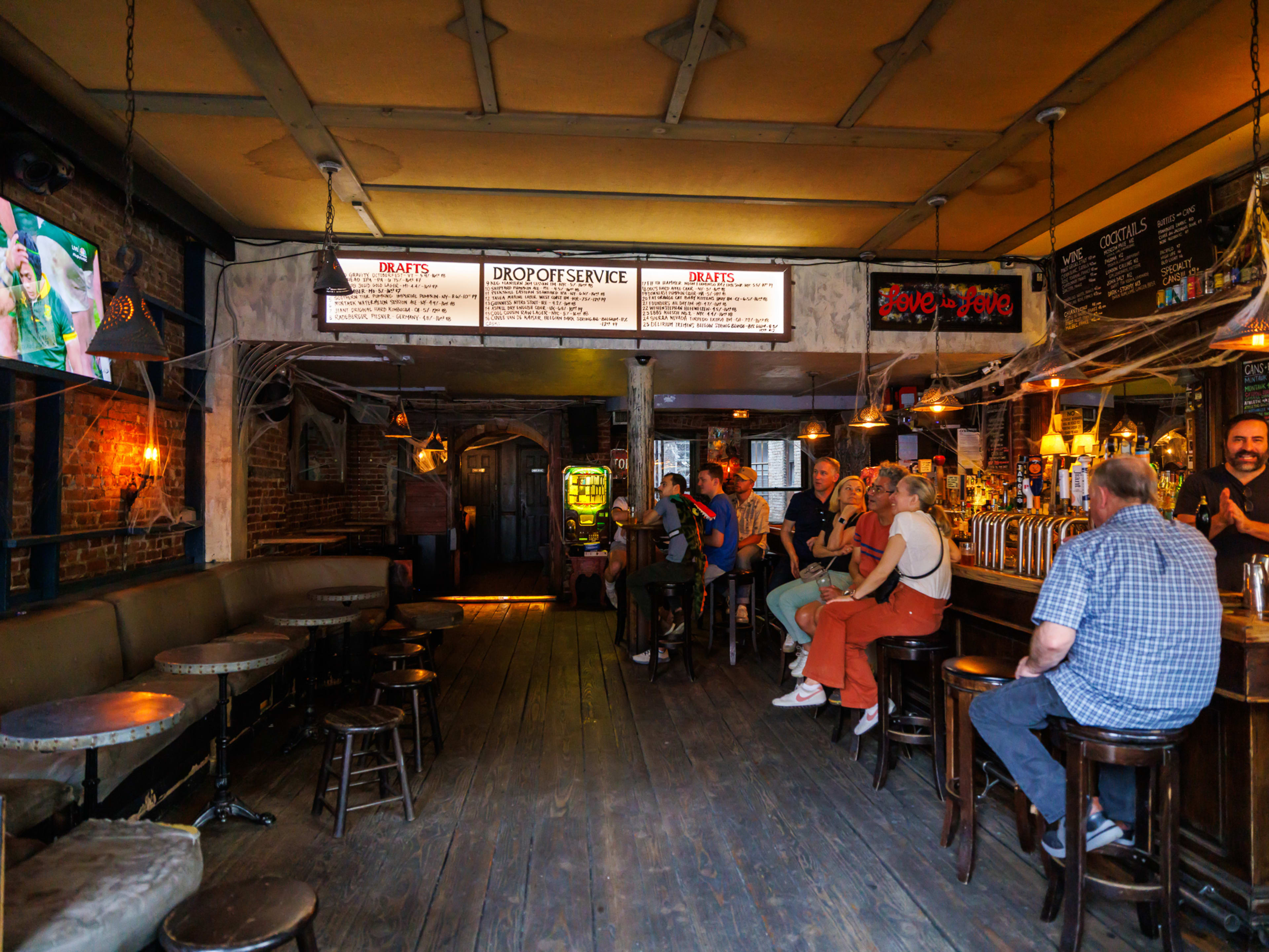 Drop Off Service interior with bar seating, booth seating, and tvs hung on a brick wall