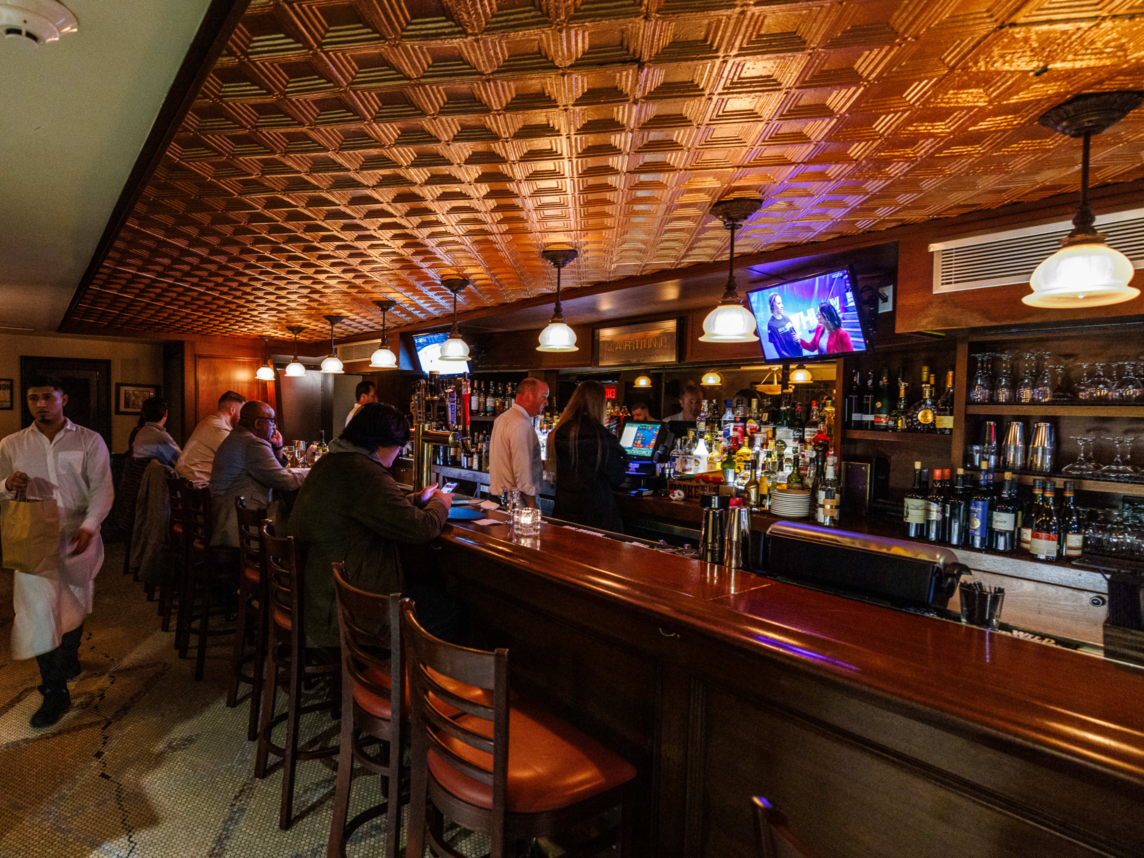 Edward's Steakhouse interiors with people seated at a long dark wooden bar under dim lighting