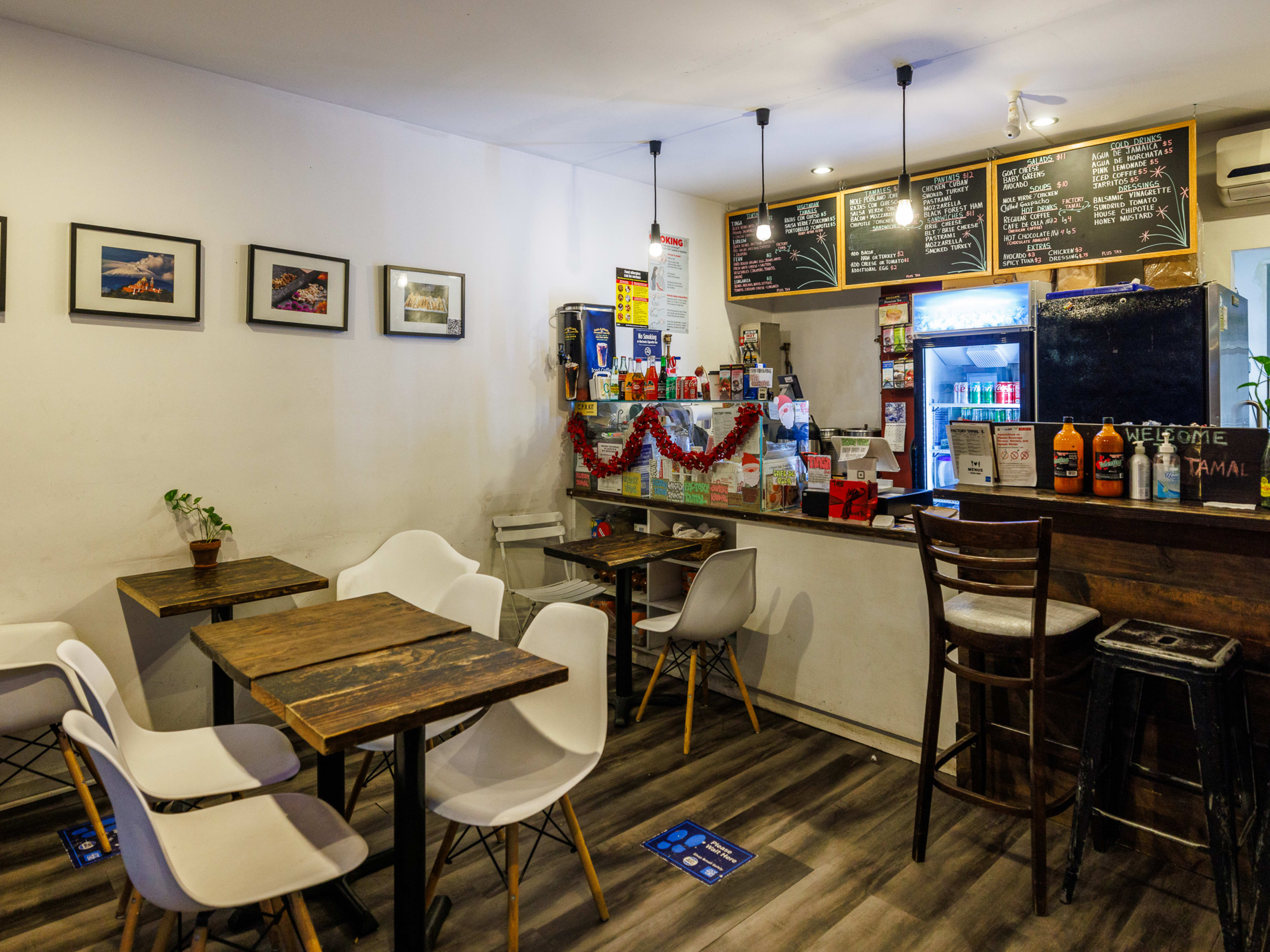 Factory Tamal interiors with square wooden tables and white chairs and chalkboard menus hanging behind the counter