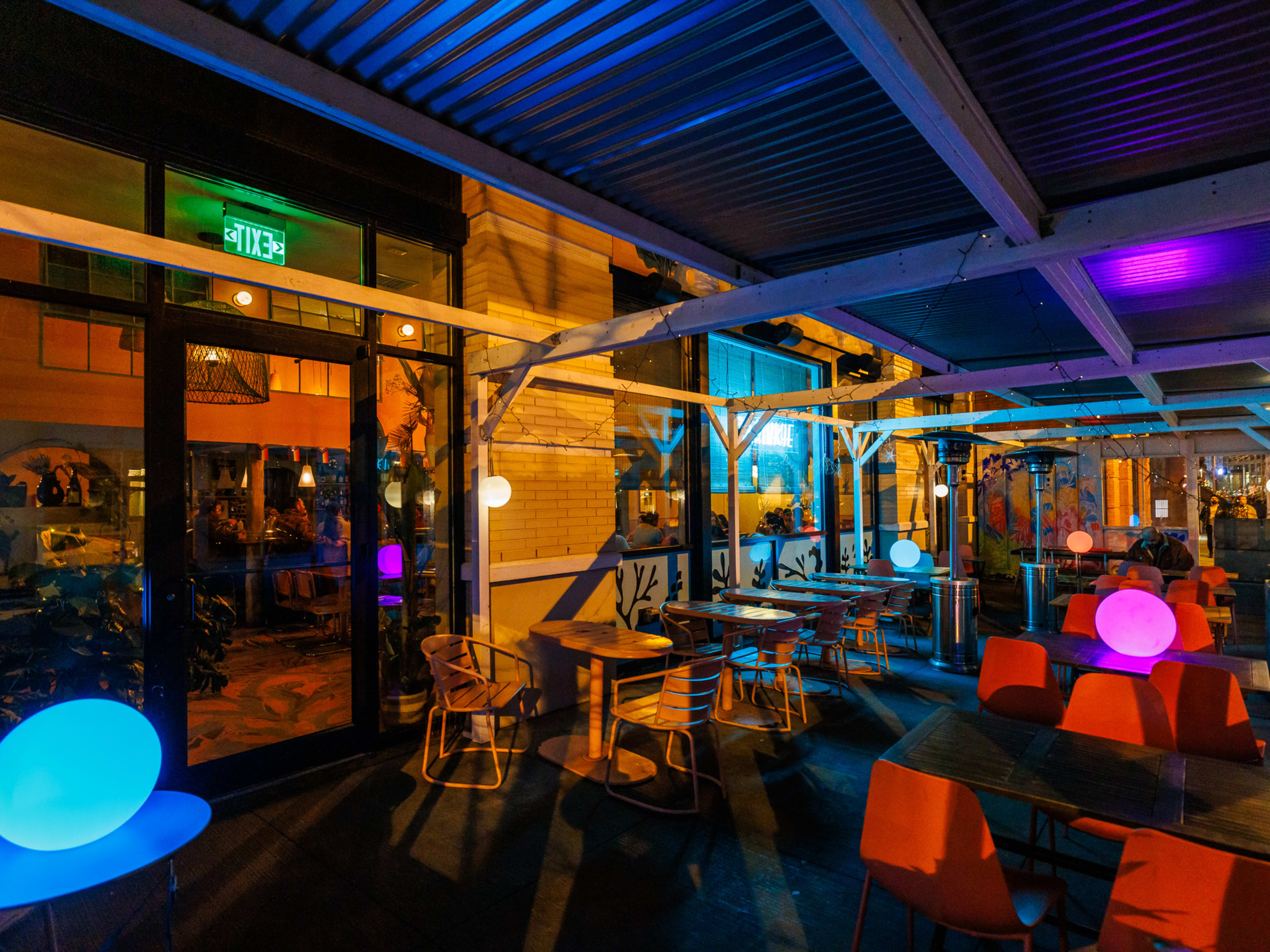 Frankie outdoor dining area at night with colorful dim lighting, empty tables, and heat lamps