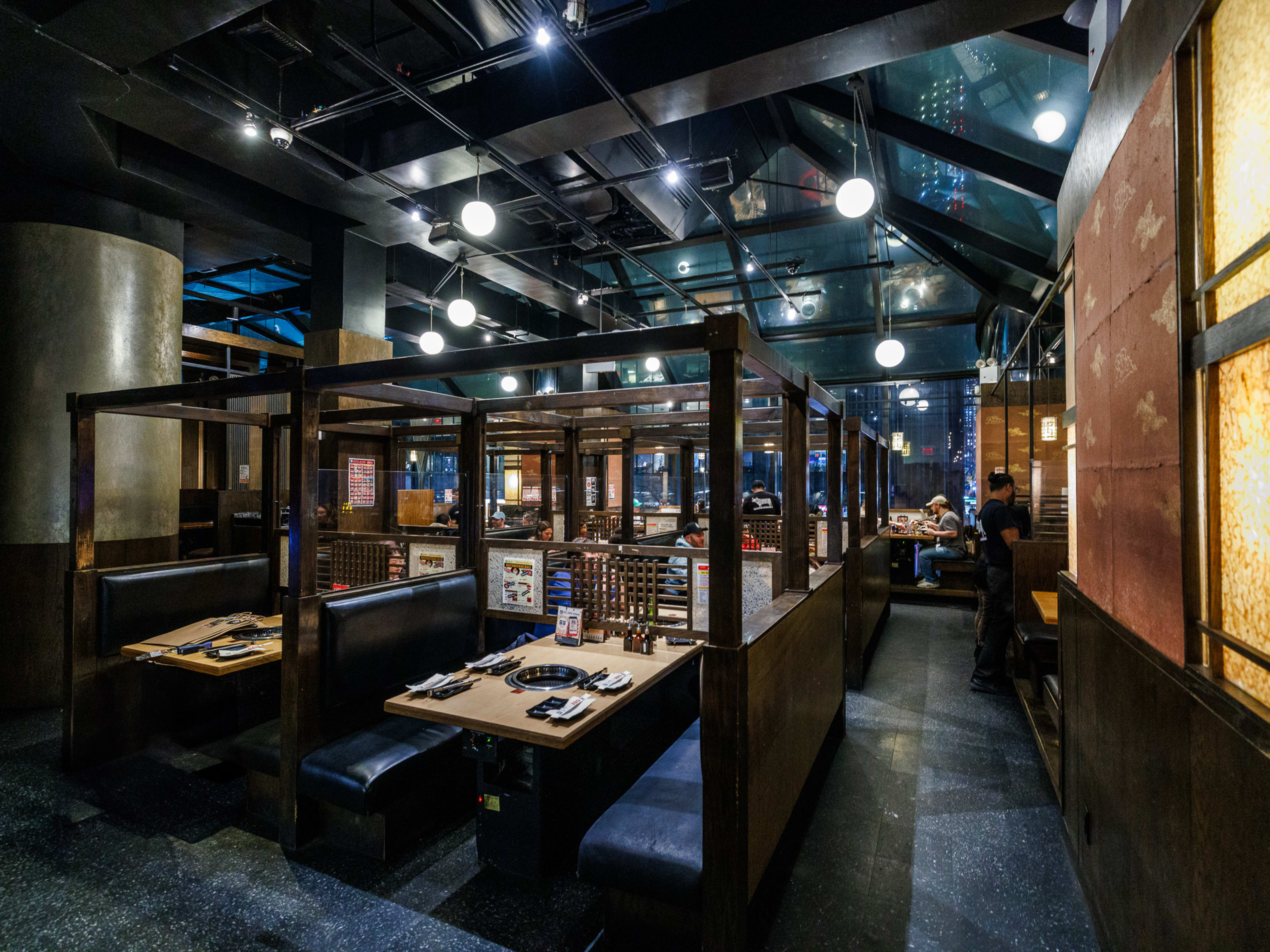 Gyu-Kaku Japanese BBQ interiors with sectioned off booths with Korean BBQ stoves on each one