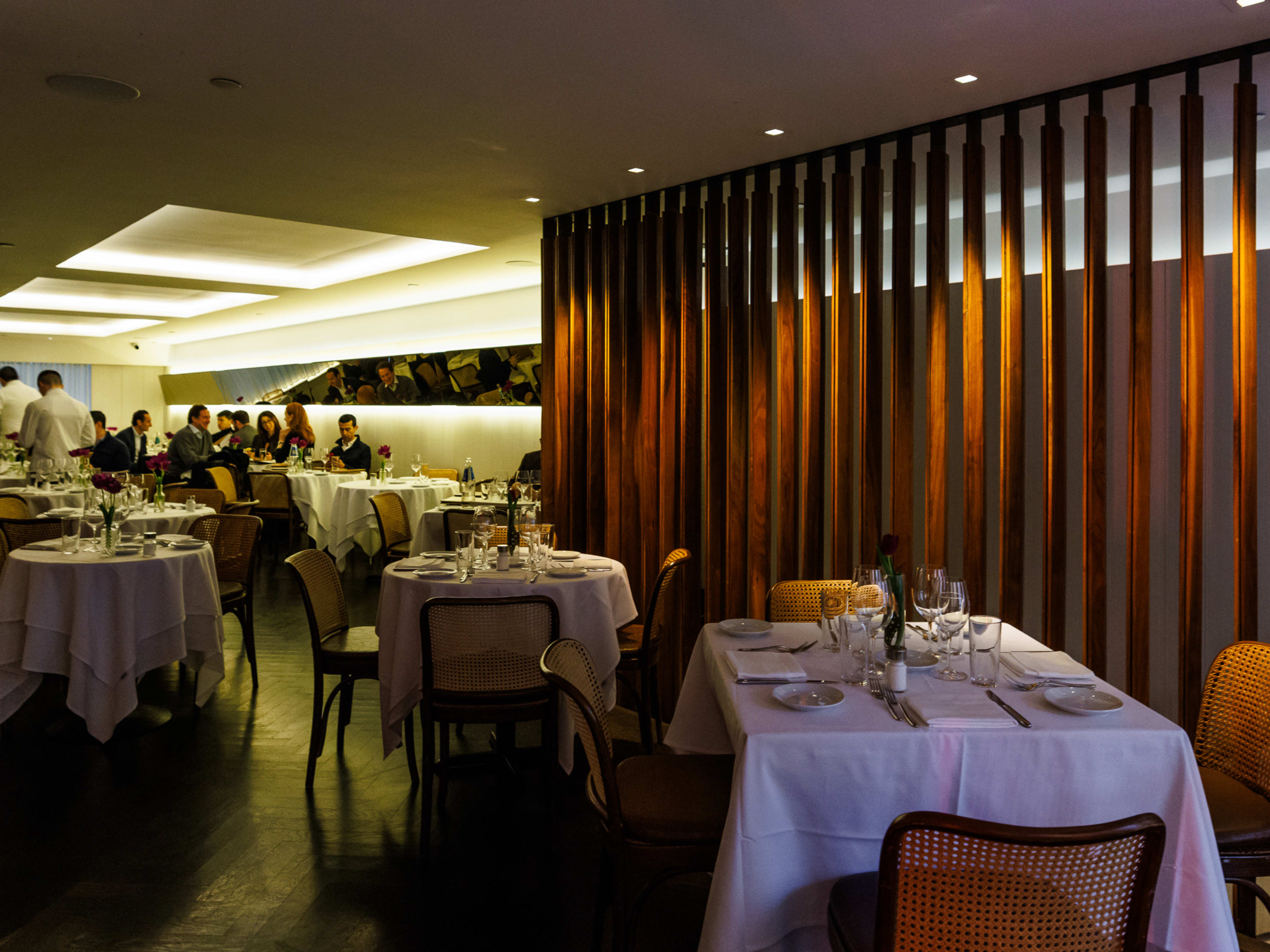 Il Gattopardo interiors with wooden beam walls, dim lighting, and formal dining tables with white tablecloths