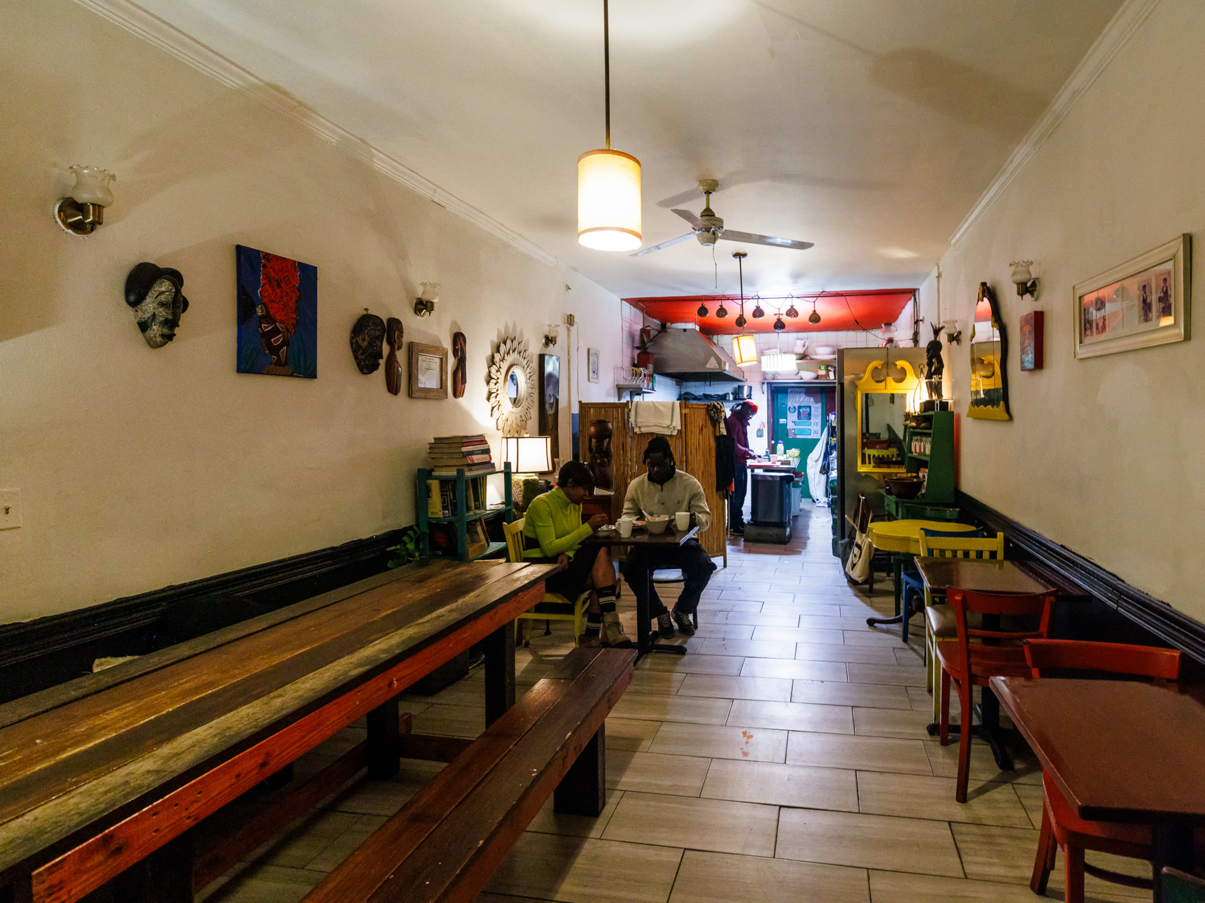 Ital Kitchen interior with a long wooden picnic table and art on the walls