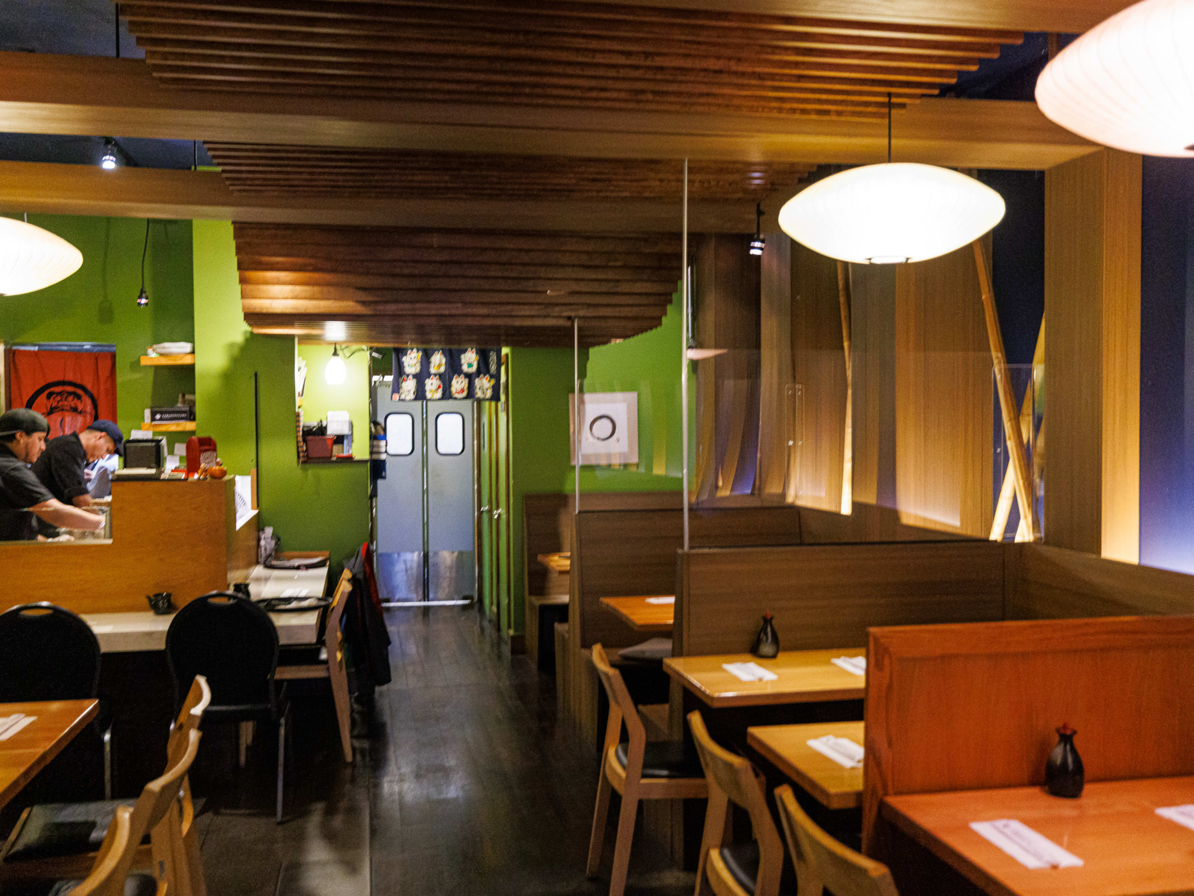 Japonica interiors with wooden booth seating, blue and green walls, and a view into the sushi kitchen