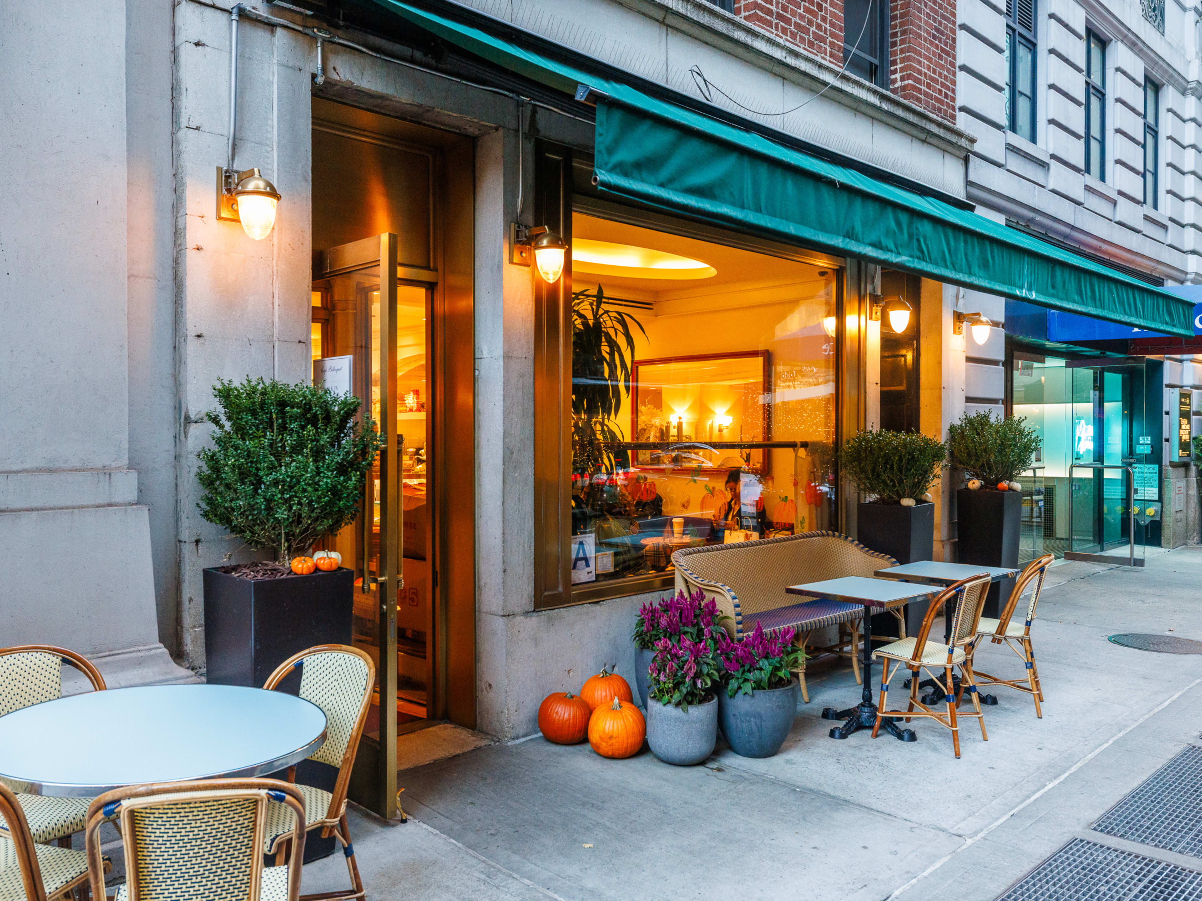 Le Bilboquet exterior with seating on the sidewalk, pumpkins and flowers on display by the door, and a large window with a view into the restaurant